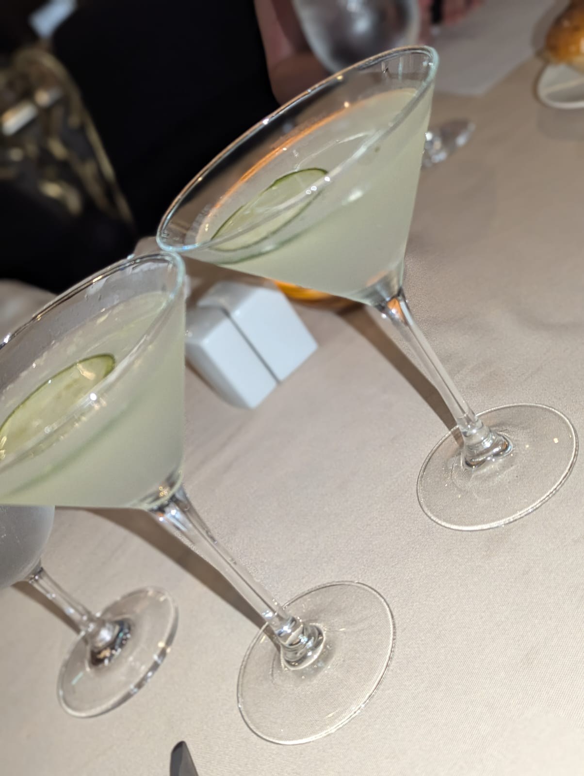 Two cucumber-garnished martinis on a white tablecloth at a Harmony of the Seas specialty restaurant.