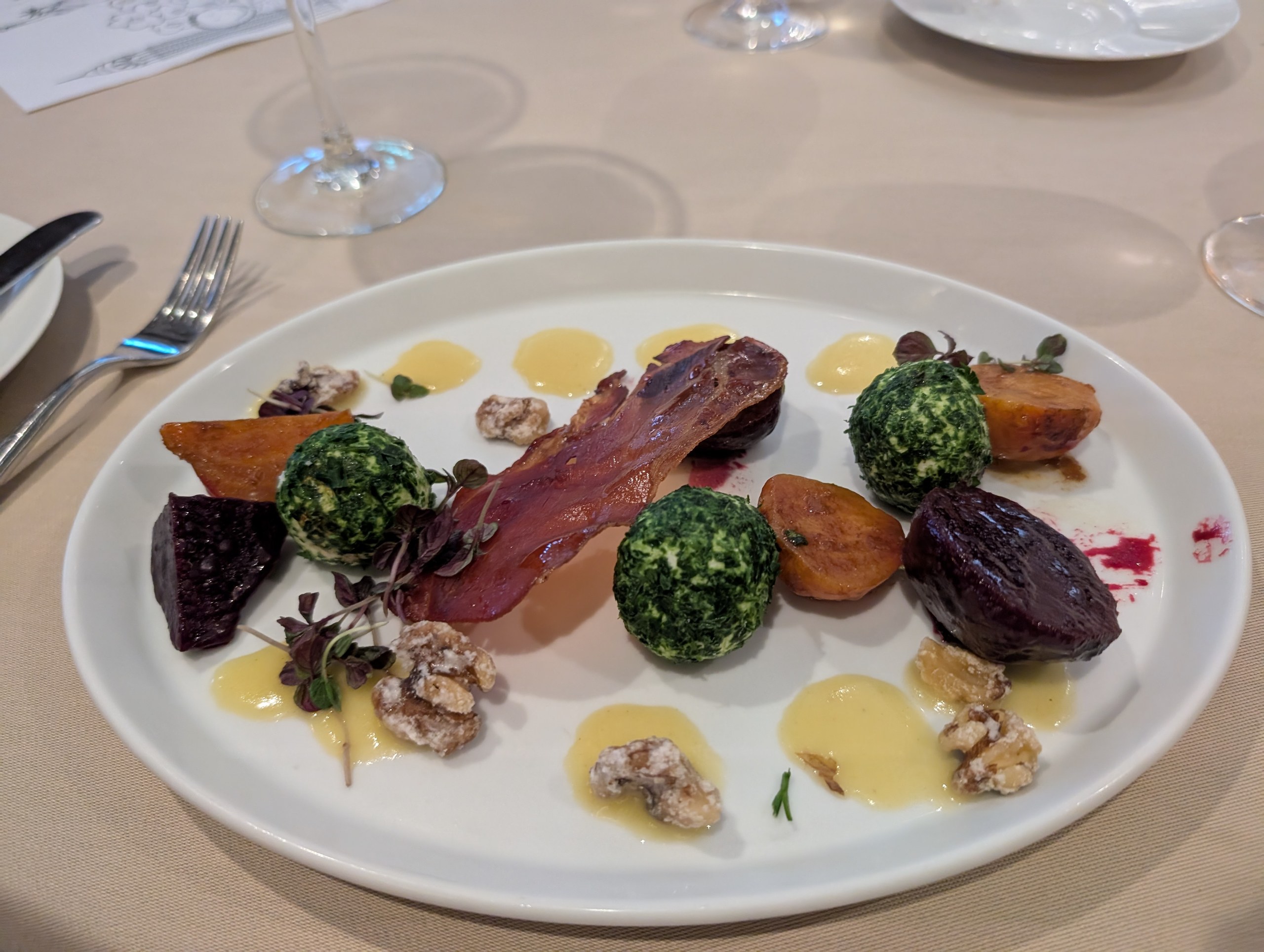 An artfully plated beet salad with herbed goat cheese spheres, candied walnuts, and crispy prosciutto at Wonderland, Royal Caribbean's Alice-themed restaurant.