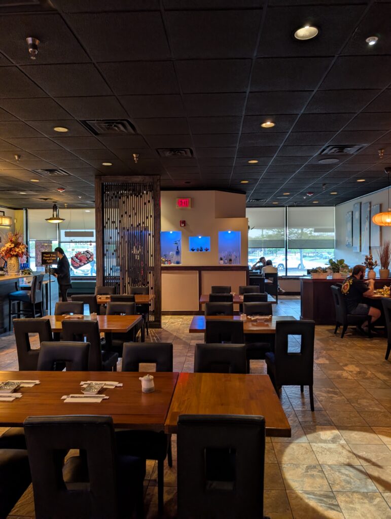 Modern dining room at Tekka Sushi with wooden tables, dark leather chairs, and a slatted partition