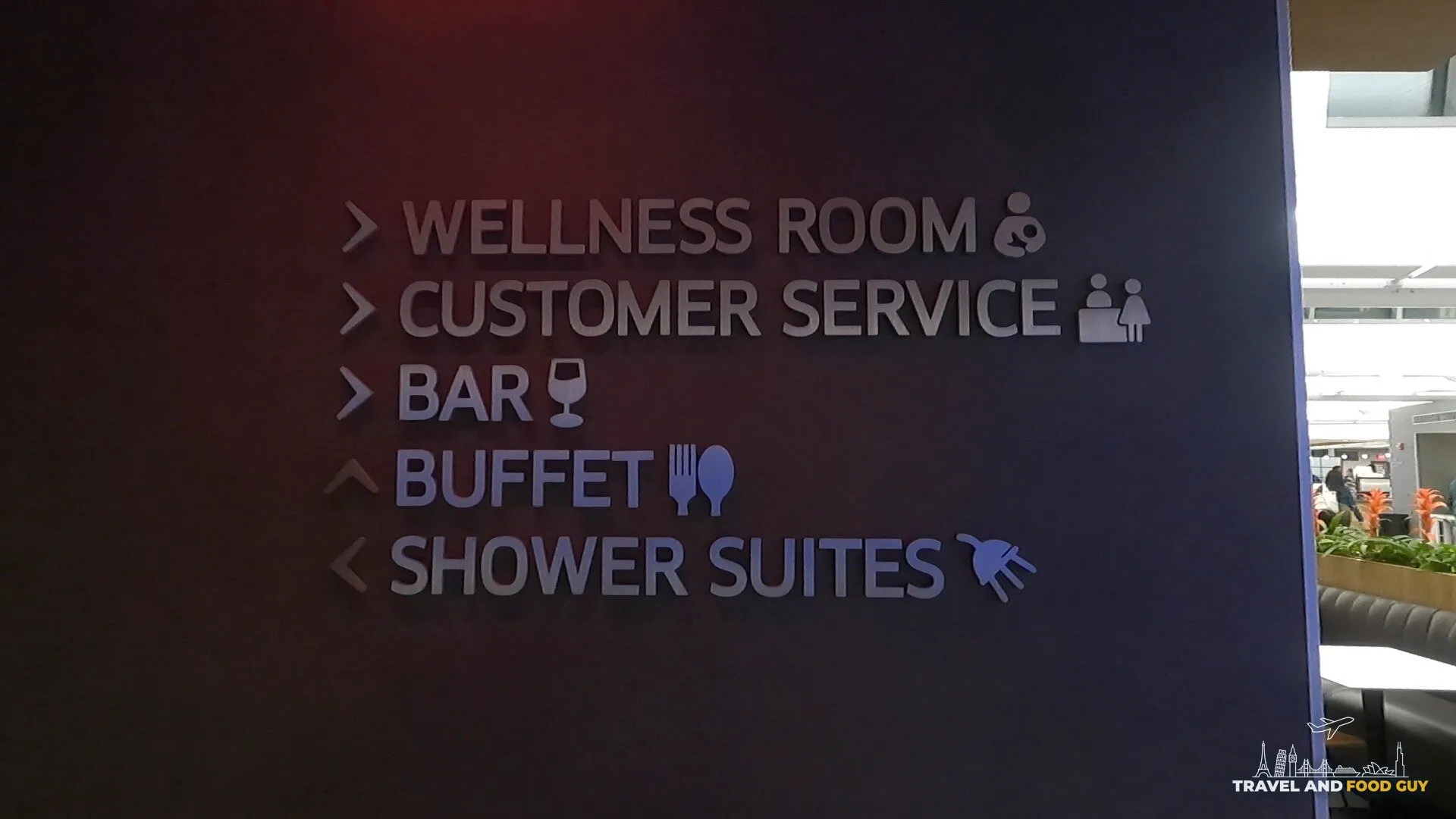 Amenities wayfinding sign at the United Club Newark Gate C123 pointing to wellness room, customer service, bar, buffet, and shower suites