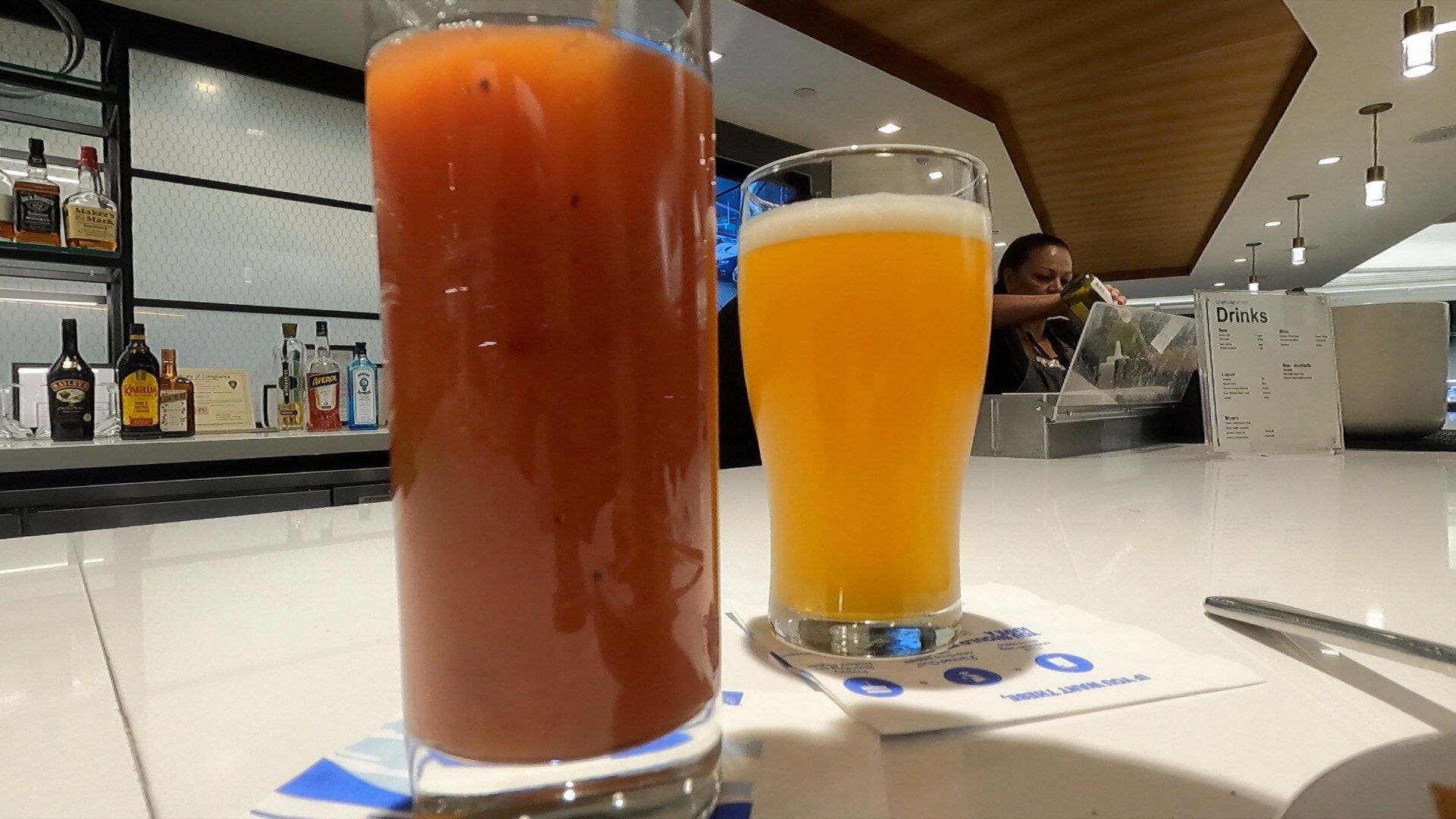 Bloody mary and a wheat beer on the bar at the United Club Newark, spirits wall in the background