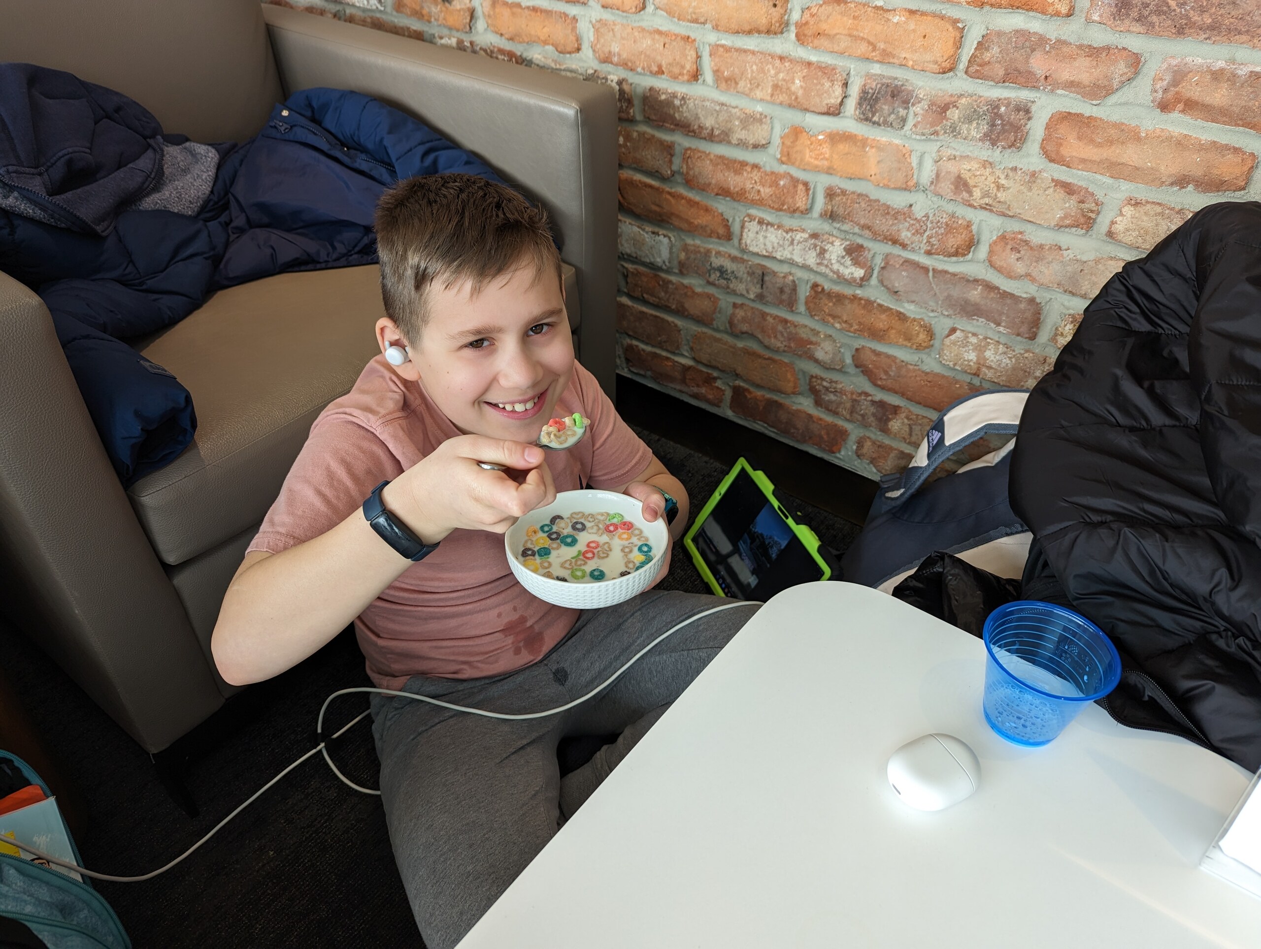 Josh smiling over a bowl of Froot Loops at the cereal bar inside the United Club at Newark Terminal A during a long delay