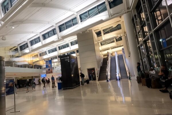 The atrium and escalator leading up to the United Club at Newark Terminal A, with the United Club tower sign overhead