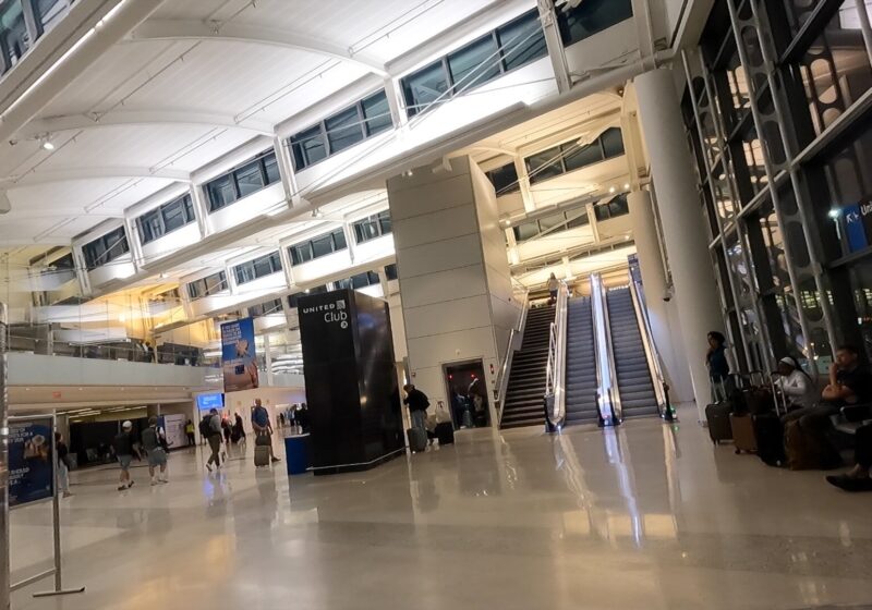 The atrium and escalator leading up to the United Club at Newark Terminal A, with the United Club tower sign overhead