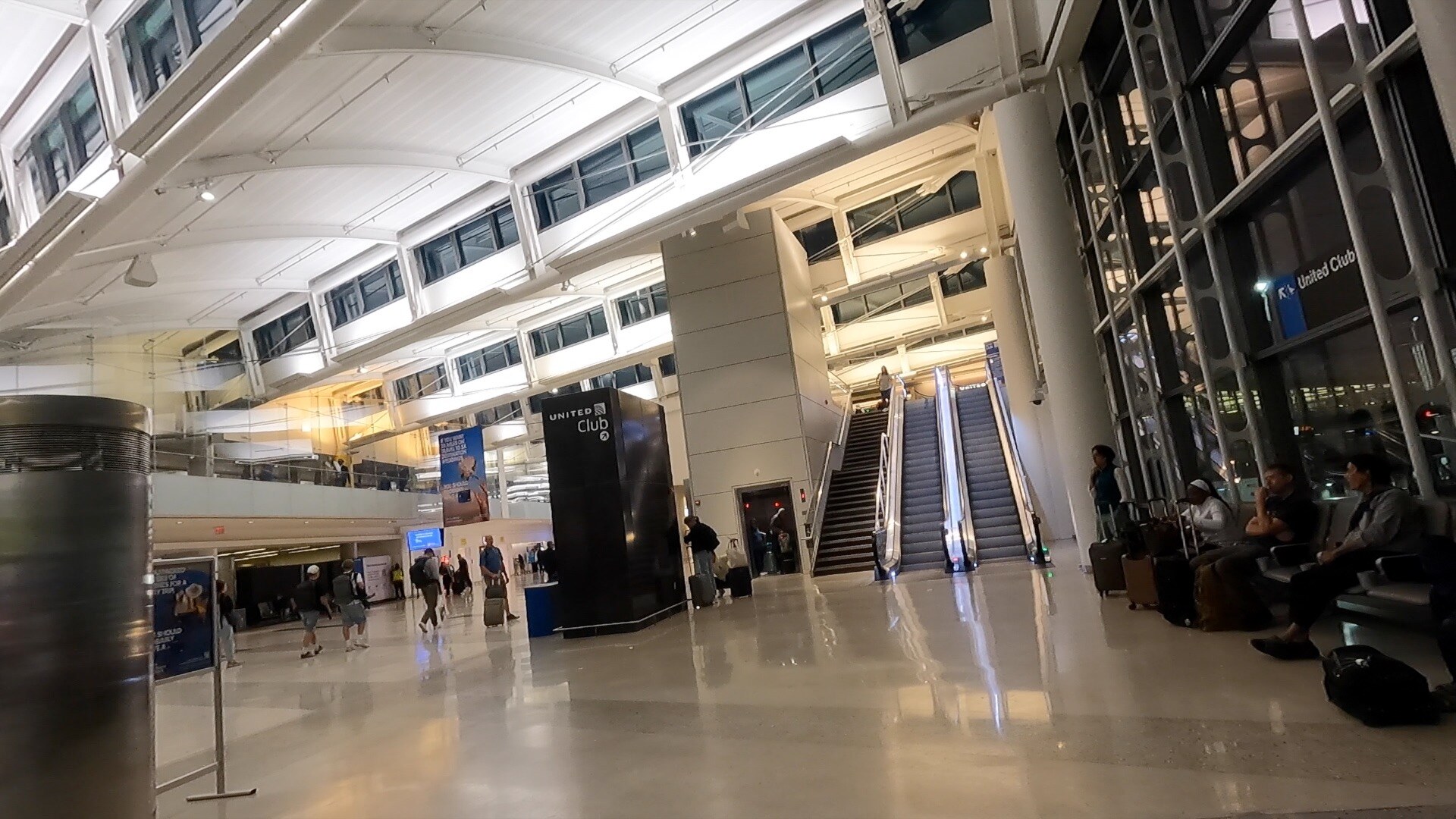 The atrium and escalator leading up to the United Club at Newark Terminal A, with the United Club tower sign overhead