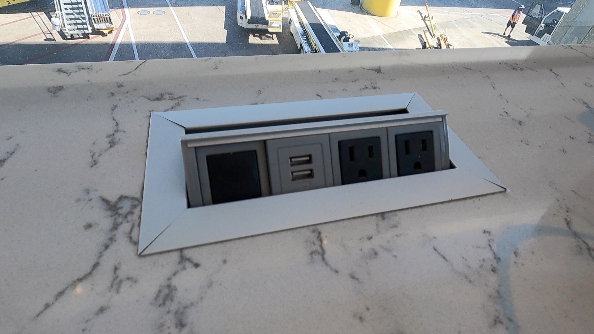 Pop-up power station with two AC outlets and dual USB ports built into a marble window counter at the United Club Newark