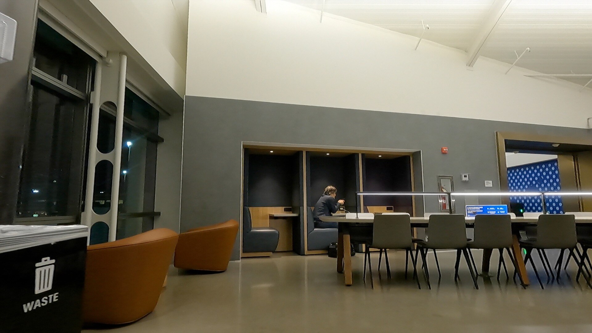 Private work pods next to a long communal table inside the United Club at Newark Terminal A
