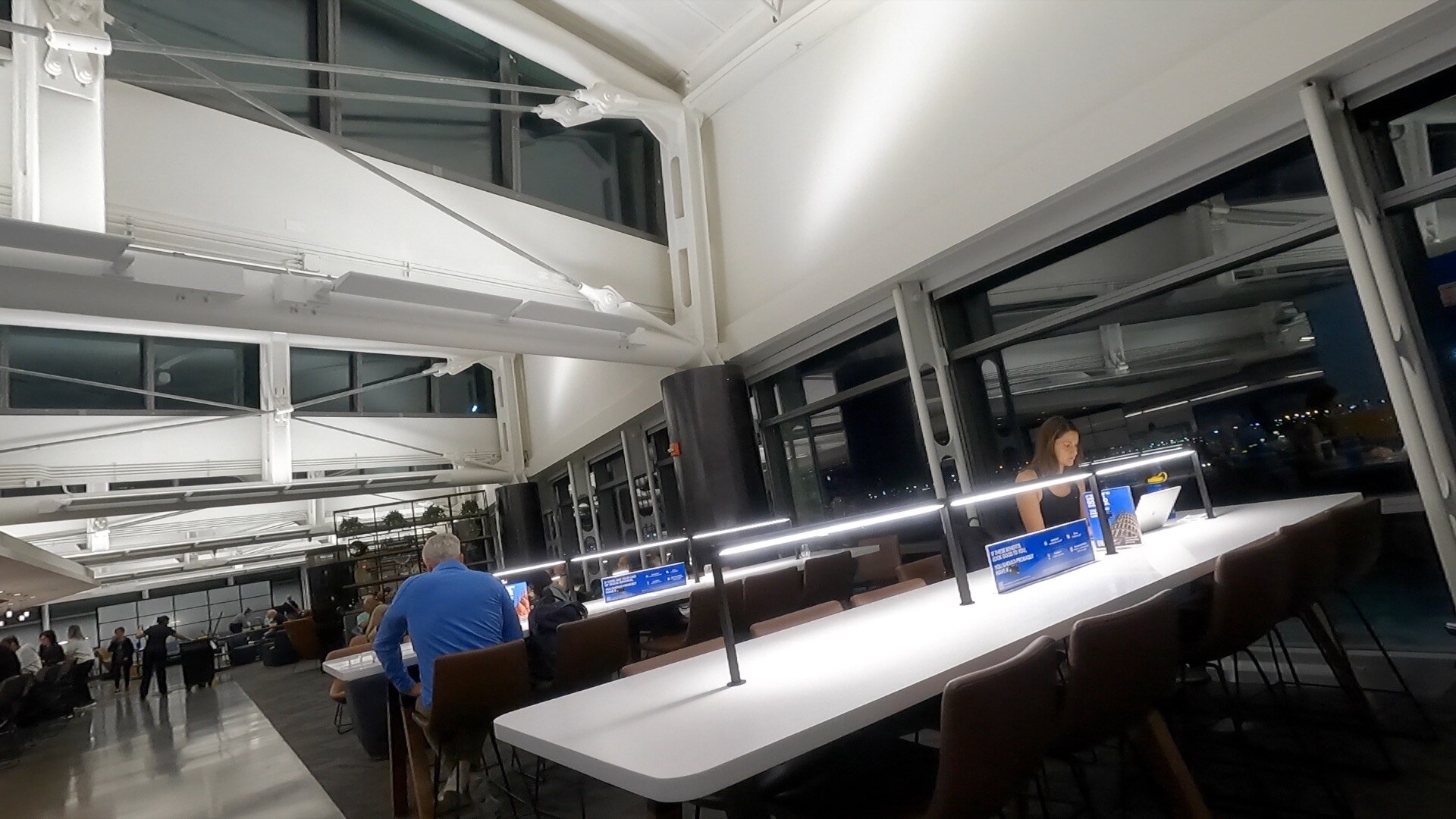 Long workspace counter at the United Club Newark with task lamps and a view of the night tarmac
