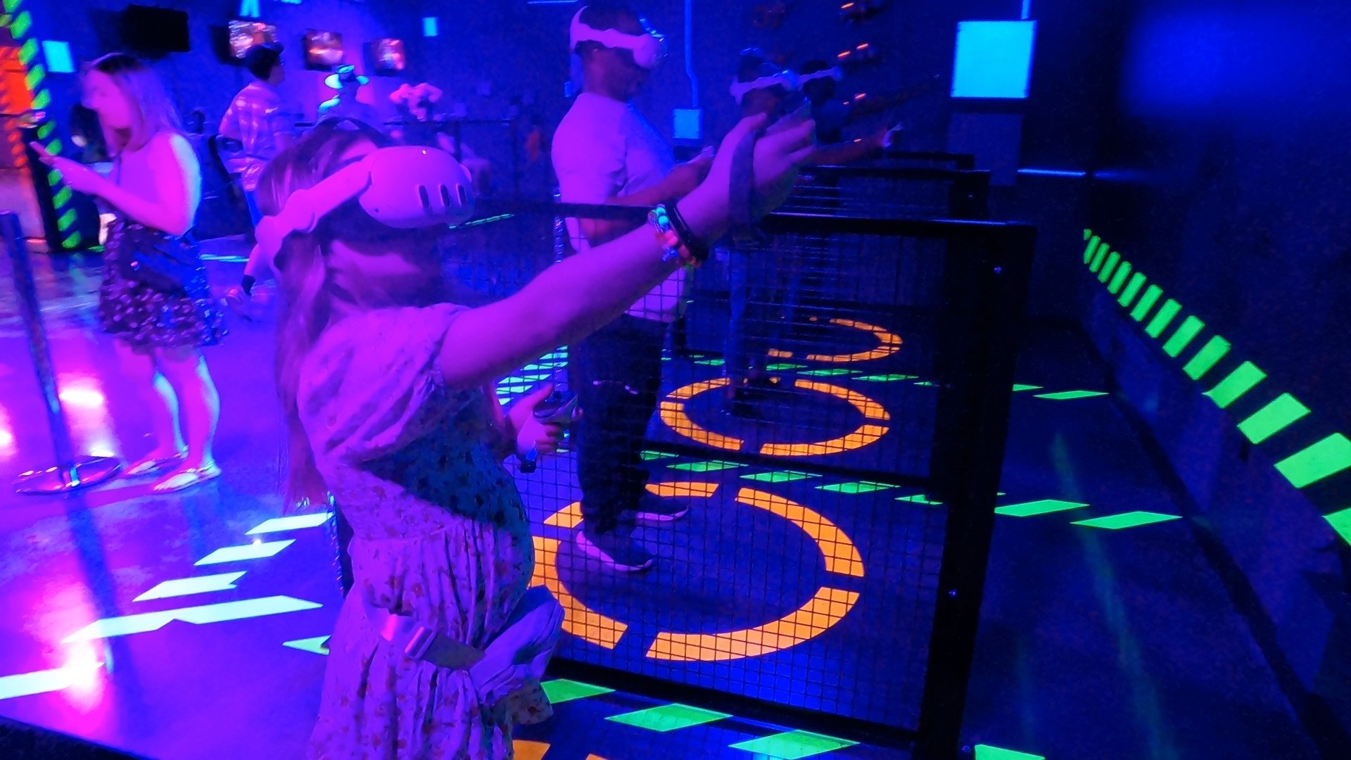 Emily wearing a VR headset and aiming a tracked controller at an Area 15 mixed reality attraction