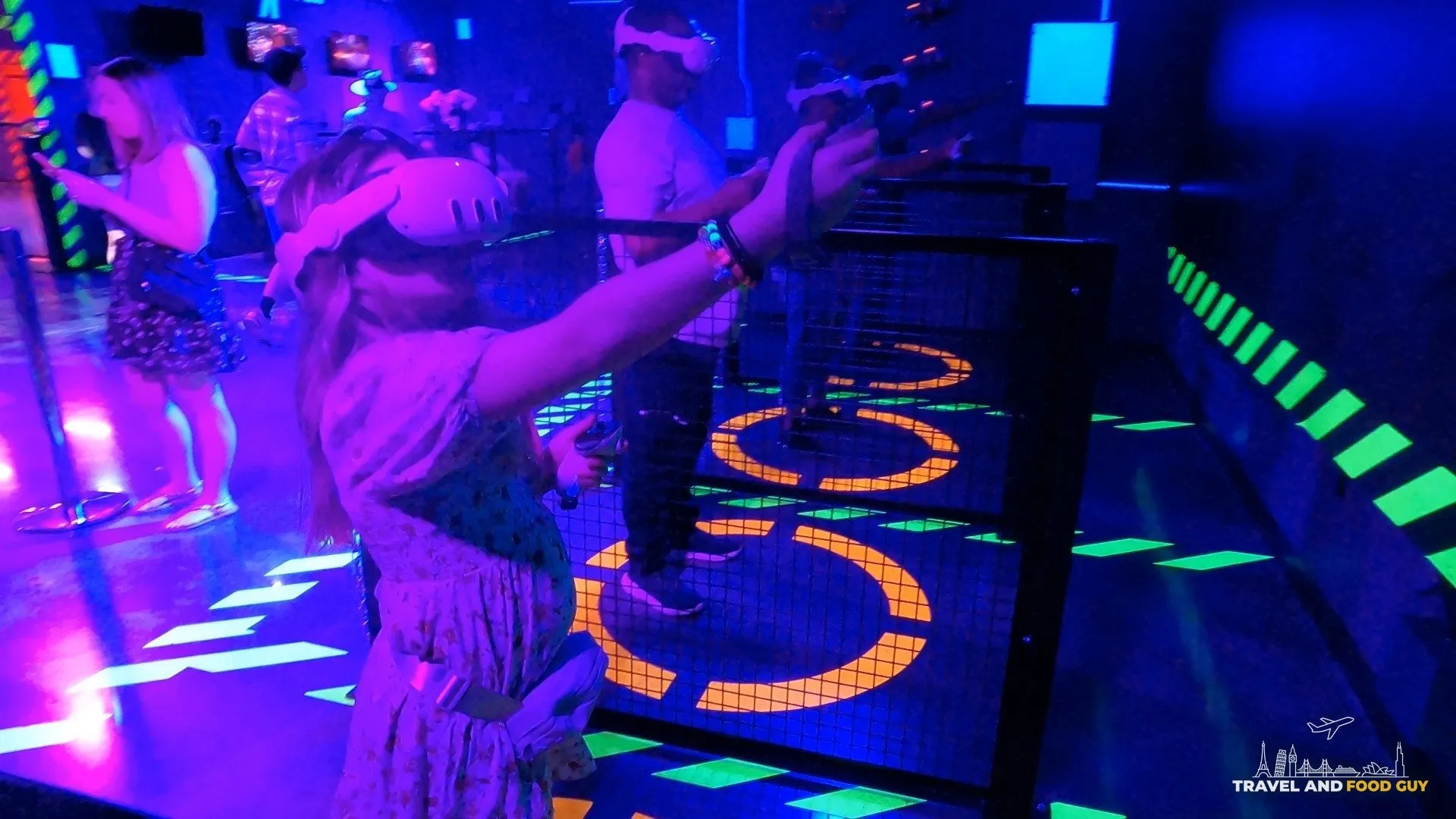 Emily wearing a VR headset and aiming a tracked controller at an Area 15 mixed reality attraction