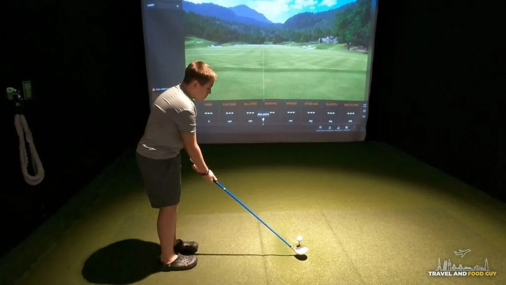 Josh setting up a tee shot in the Five Iron Golf simulator at Area 15