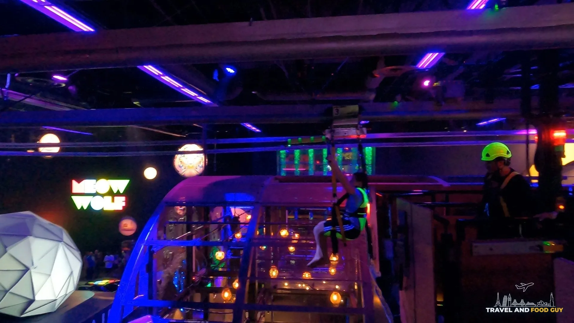 A rider zips overhead on the Halleys Comet zip line above the Area 15 concourse