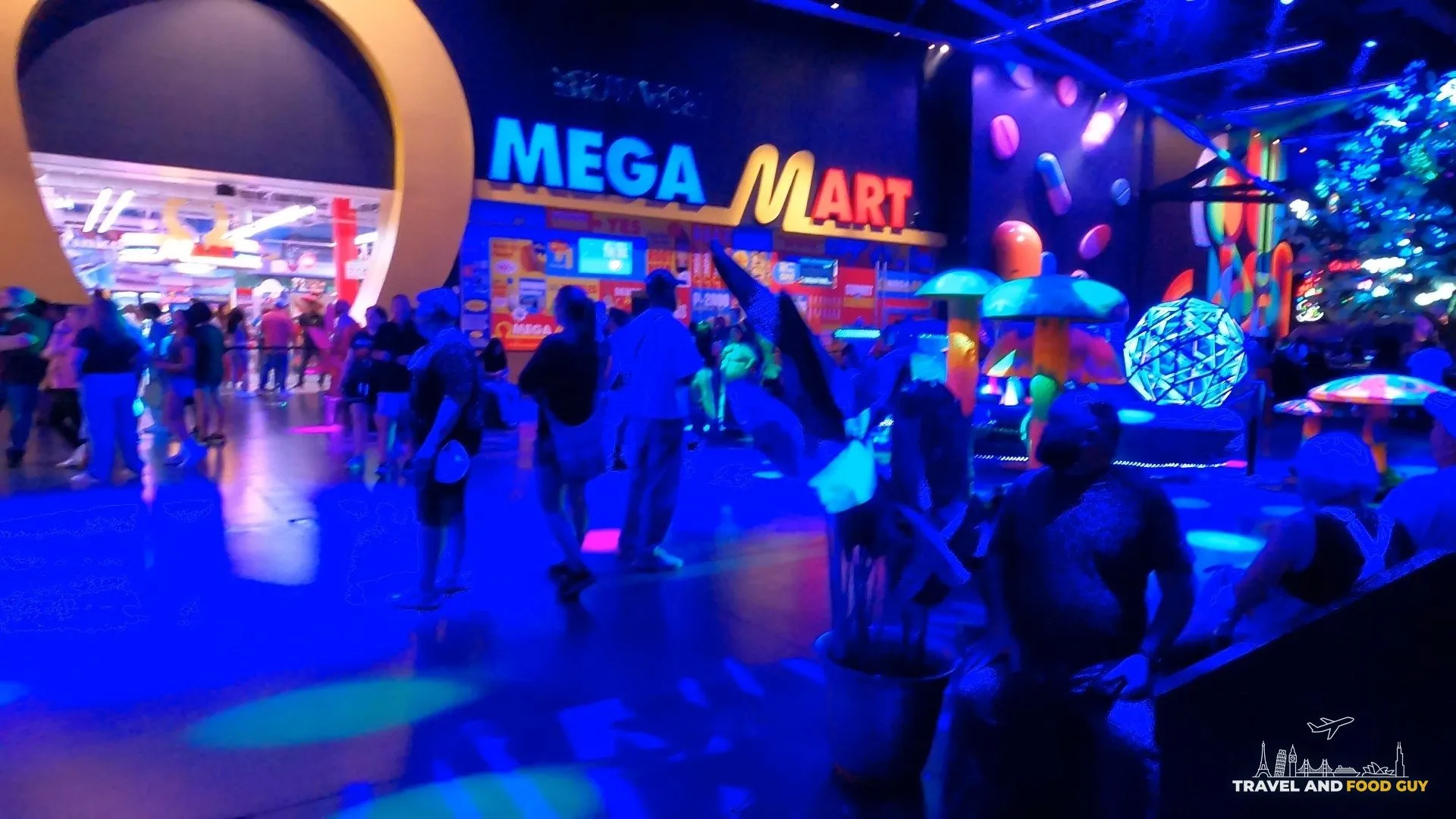 The Mega Mart neon entrance from the Area 15 concourse with crowds and immersive props
