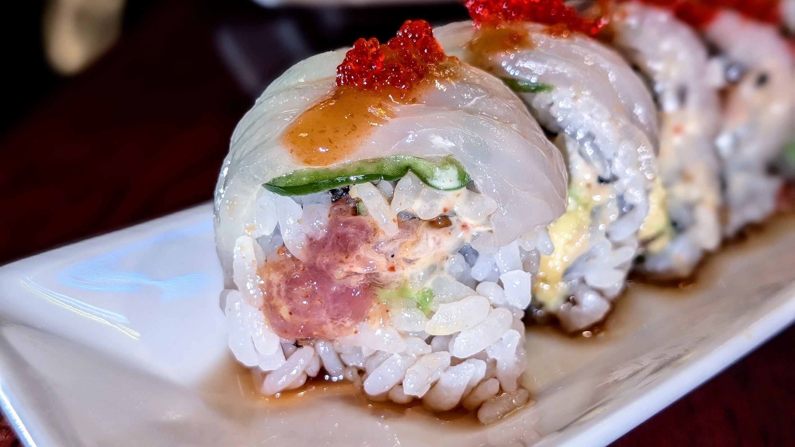 Close-up of the Fire Bird roll at Ari Sushi, thinly sliced fluke draped over the top with a stripe of red tobiko