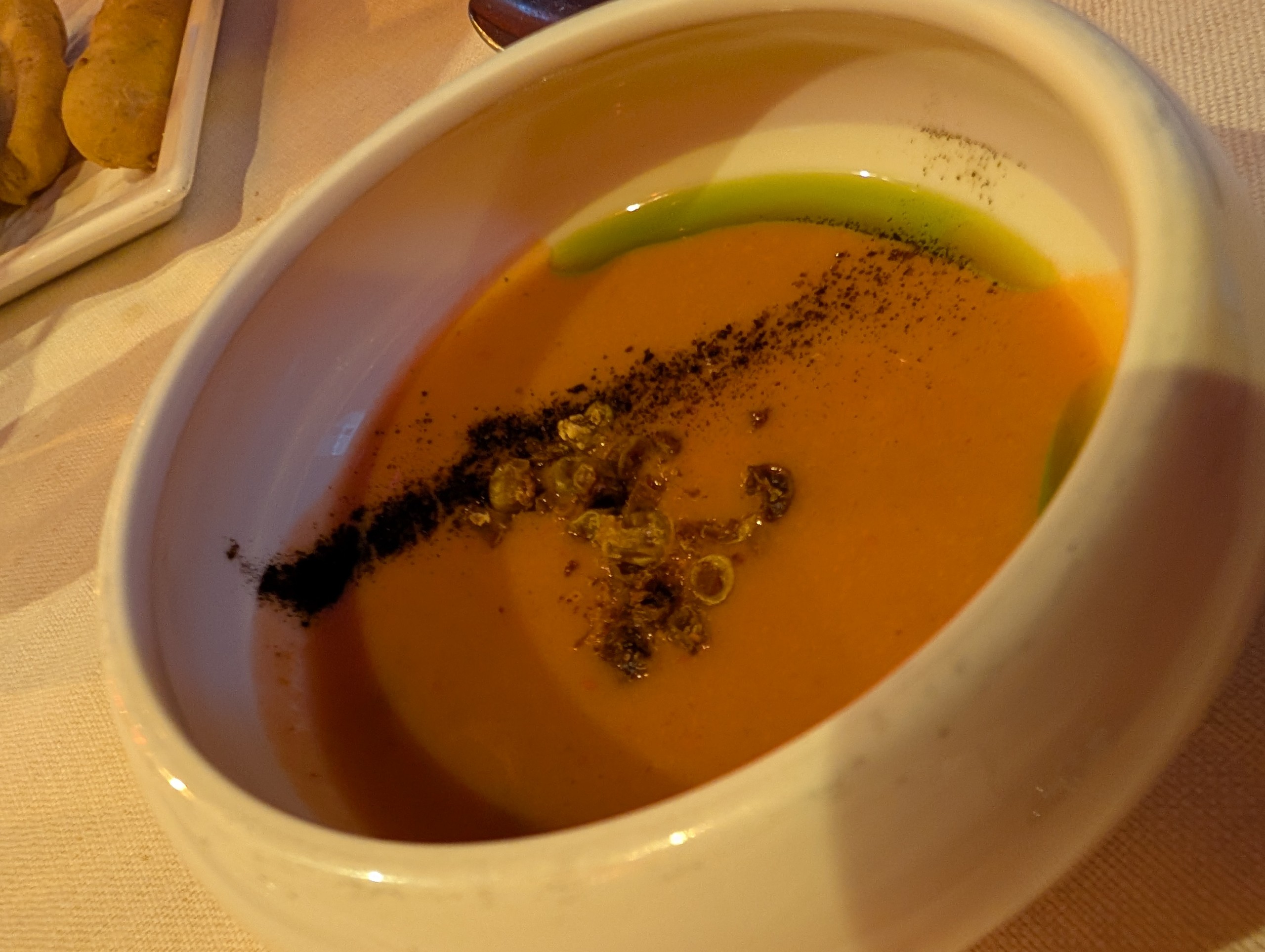 Pumpkin velouté with green herb oil drizzle and spice dust at Bistrot de Venise, Venice