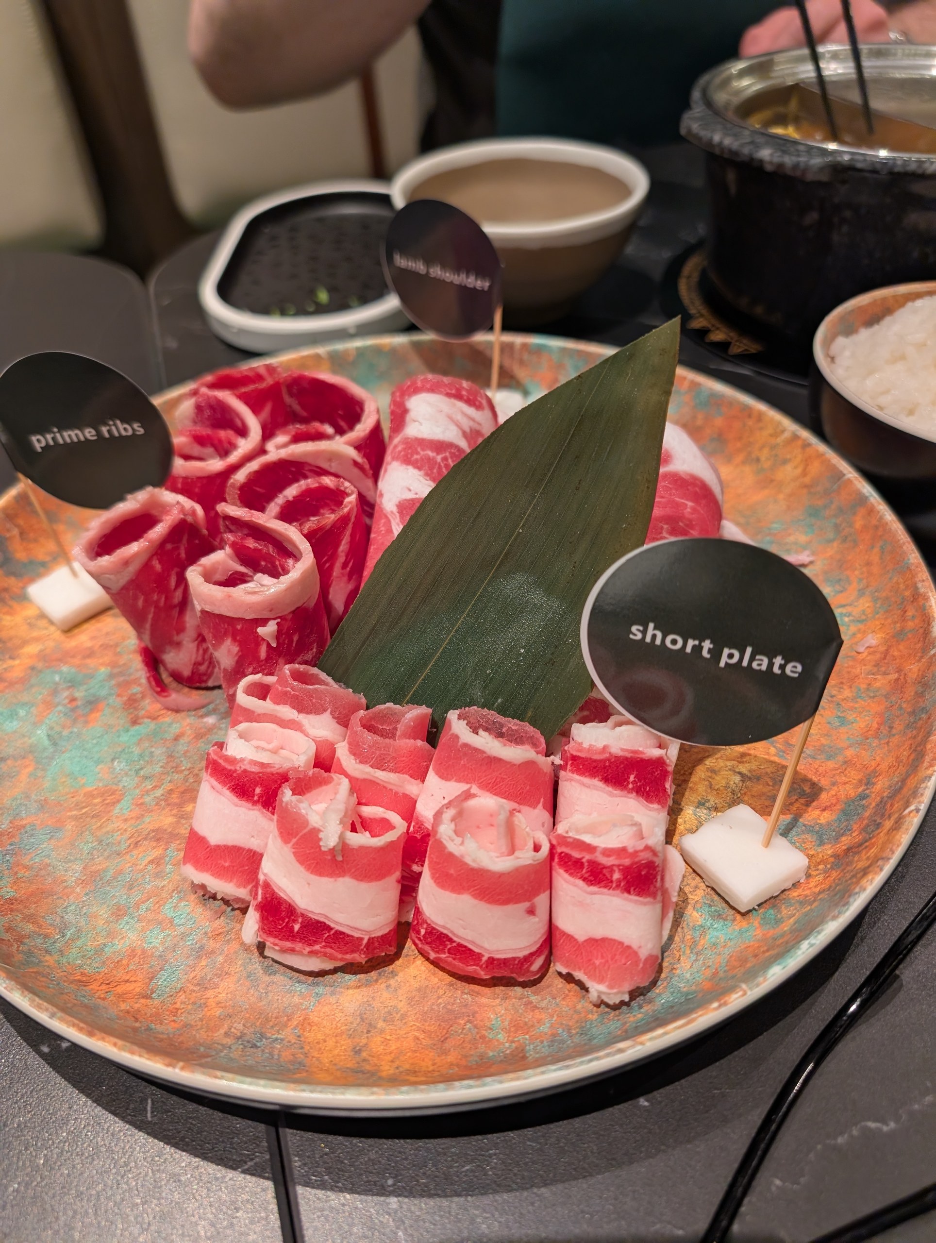Hot pot meat platter at Broth and Beyond with labeled rolls of prime ribs, lamb shoulder, and short plate