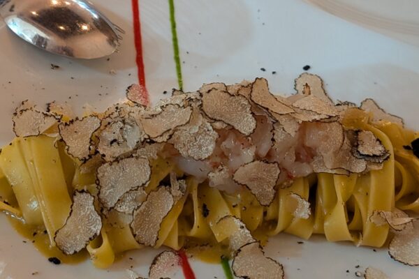 Fresh tagliatelle topped with generous shavings of white truffle, plated with red and green sauce dots in Italian-flag colors at Cantinetta delle Terme, Florence