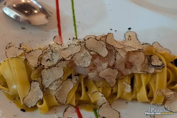 Fresh tagliatelle topped with generous shavings of white truffle, plated with red and green sauce dots in Italian-flag colors at Cantinetta delle Terme, Florence