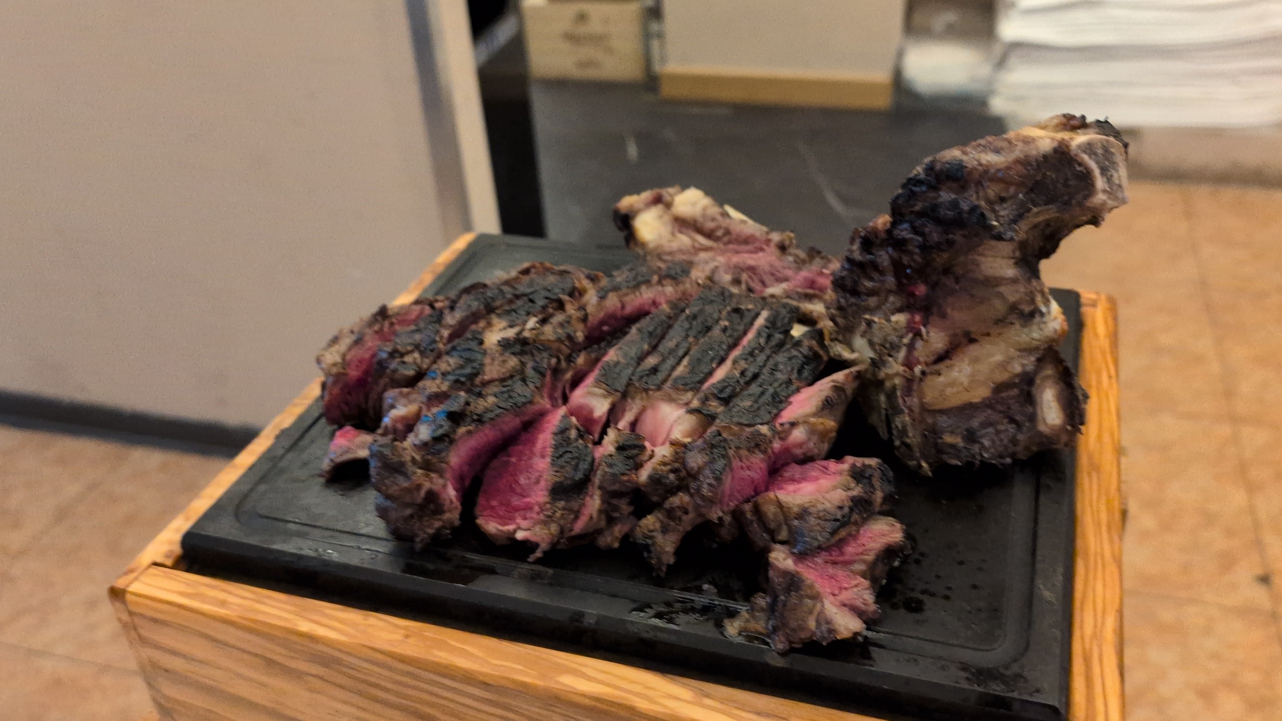 Sliced cooked bistecca alla Fiorentina, blue-rare in the middle with charred crust, presented on a black slate board at Steakhouse Da Aldone, Florence