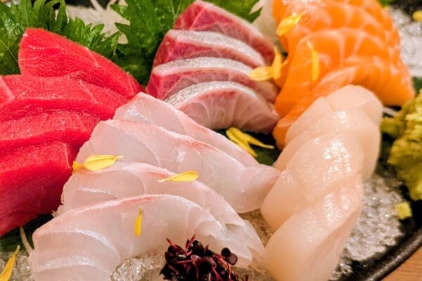 Centerpiece sashimi platter on ice featuring tuna, salmon, yellowtail belly, white fish and scallop.