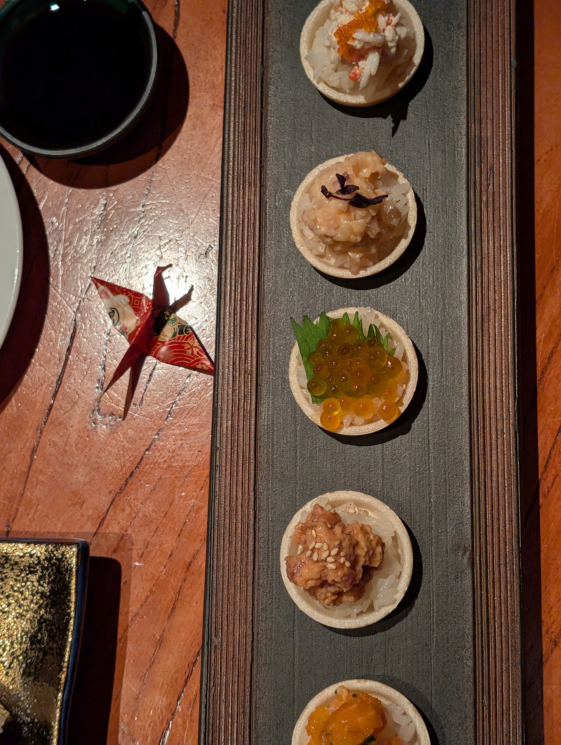 The six piece Monaka Sushi tasting board at KOMA Singapore, including ikura on shiso, salmon yuzu kosho, king crab cucumber, truffle unagi, spicy tuna, and spicy yellowtail.