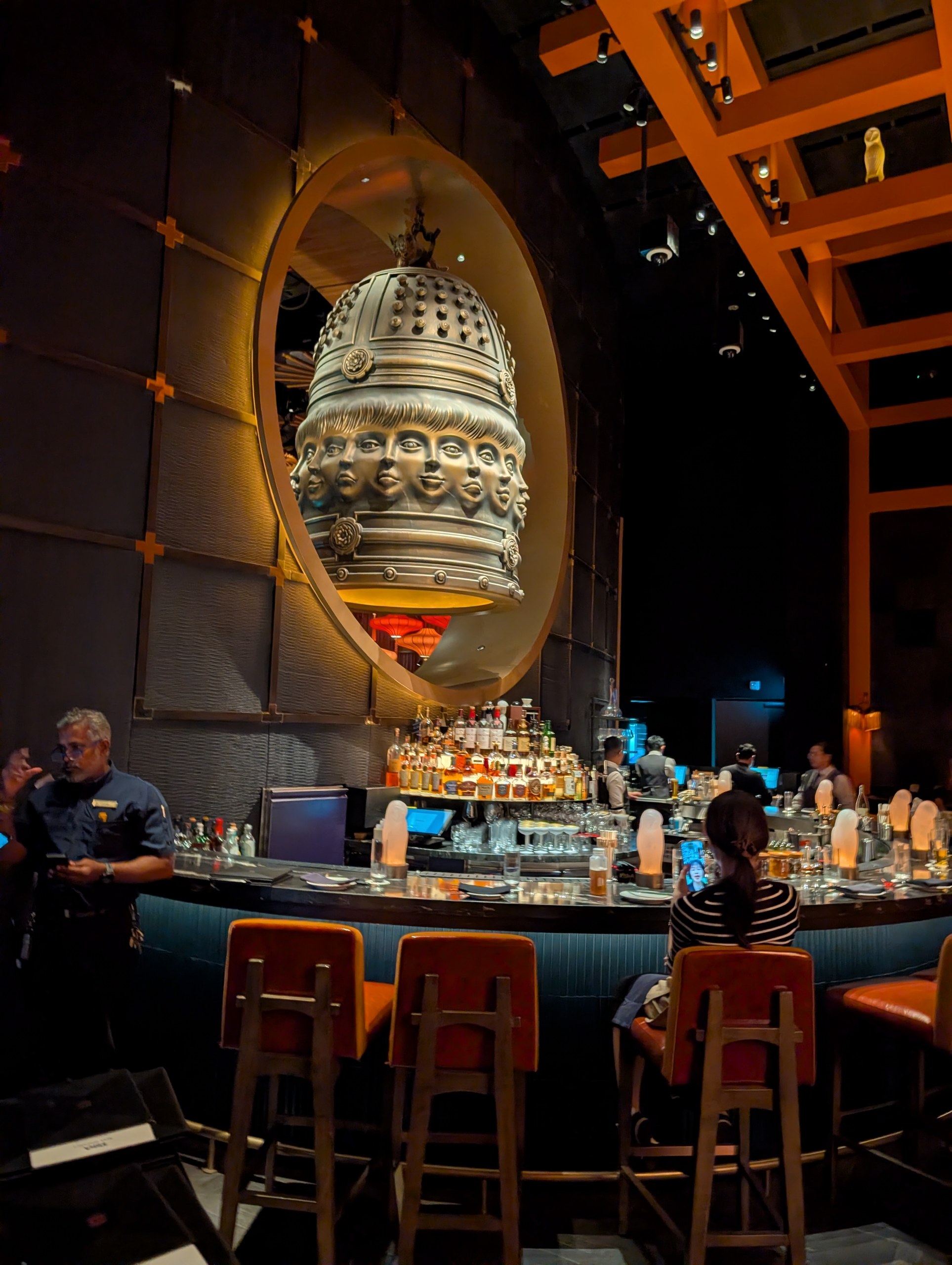 The giant bronze multi-face bell sculpture hanging over the bar at KOMA Singapore.