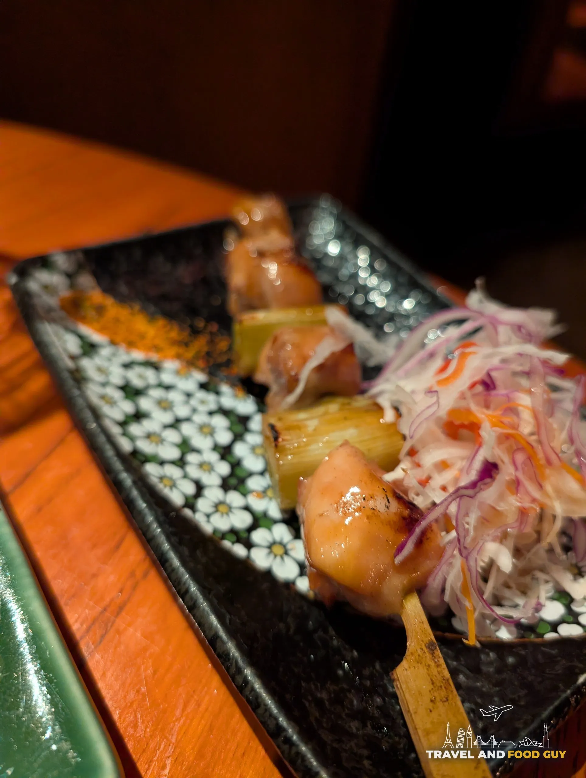 Two Negima yakitori skewers at KOMA Singapore, chicken thigh alternating with Tokyo negi, served with shaved cabbage and shichimi.