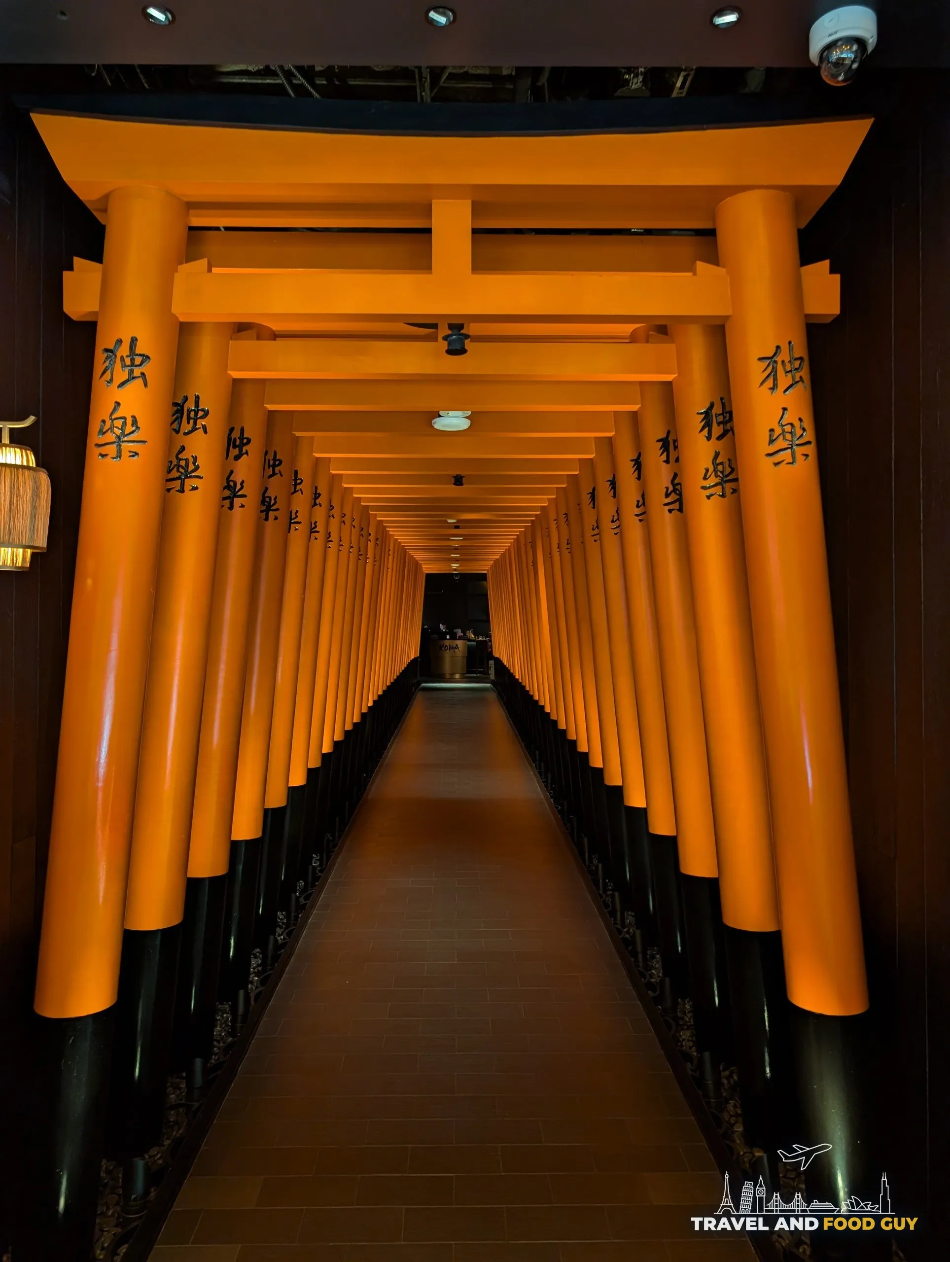 The orange torii gate hallway at the entrance of KOMA Singapore, with Japanese kanji characters across the crossbeams.