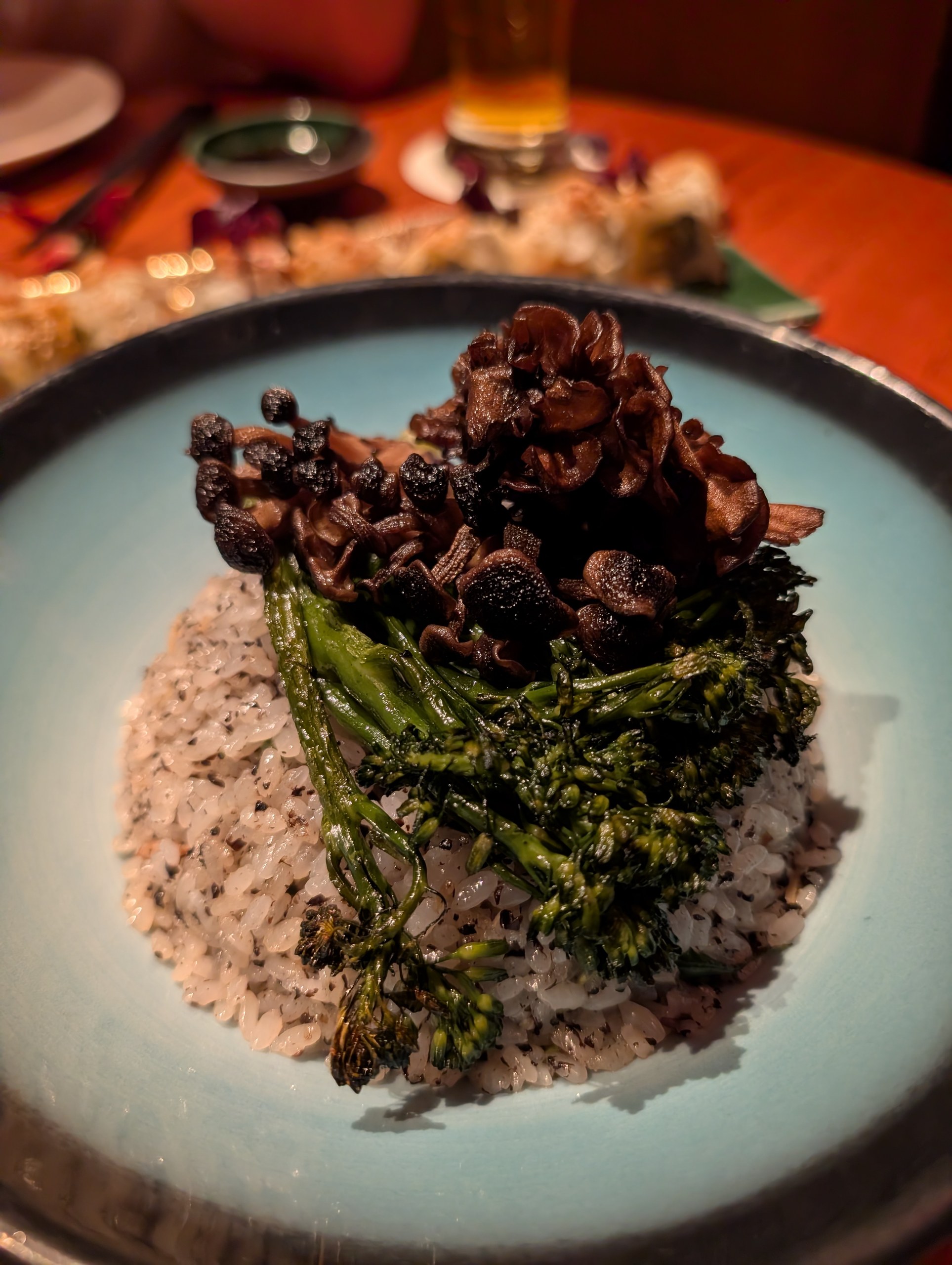 The Truffle Fried Rice at KOMA Singapore, topped with maitake and king oyster mushrooms and a stalk of broccolini.