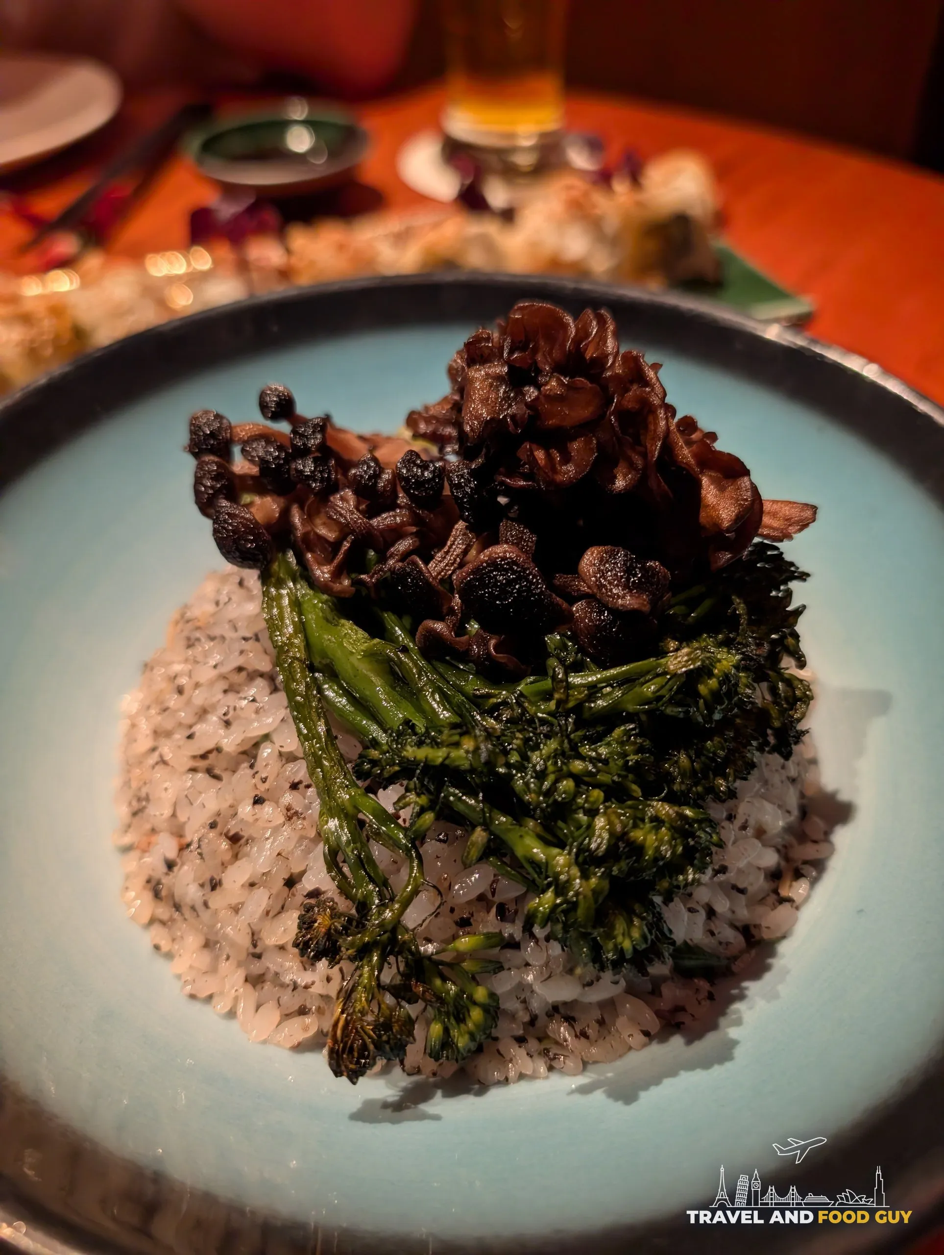The Truffle Fried Rice at KOMA Singapore, topped with maitake and king oyster mushrooms and a stalk of broccolini.