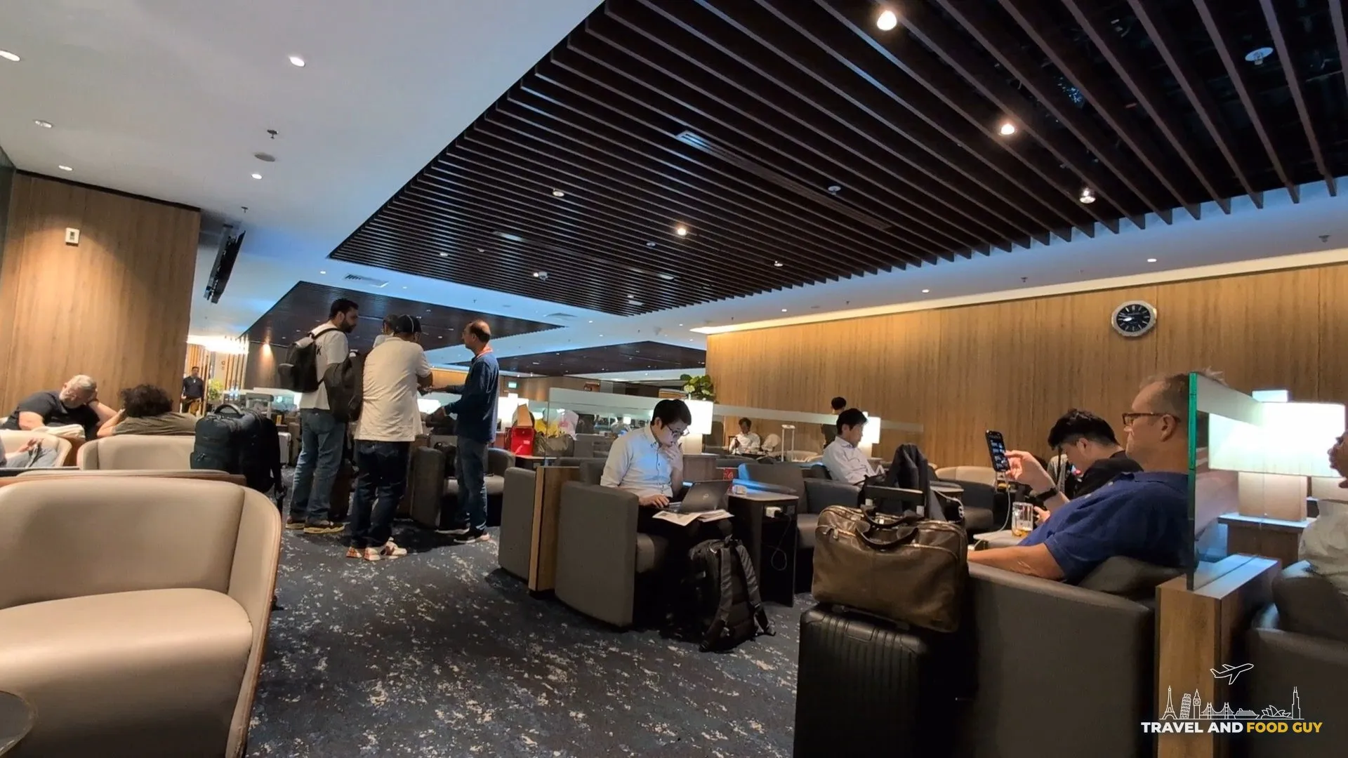 Busy evening crowd in the KrisFlyer Gold Lounge with travelers working on laptops and gathering at the buffet.
