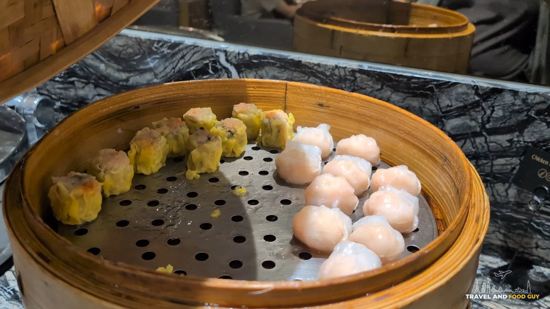 Shumai and har gow dumplings in a bamboo steamer at the KrisFlyer Gold Lounge dim sum line.