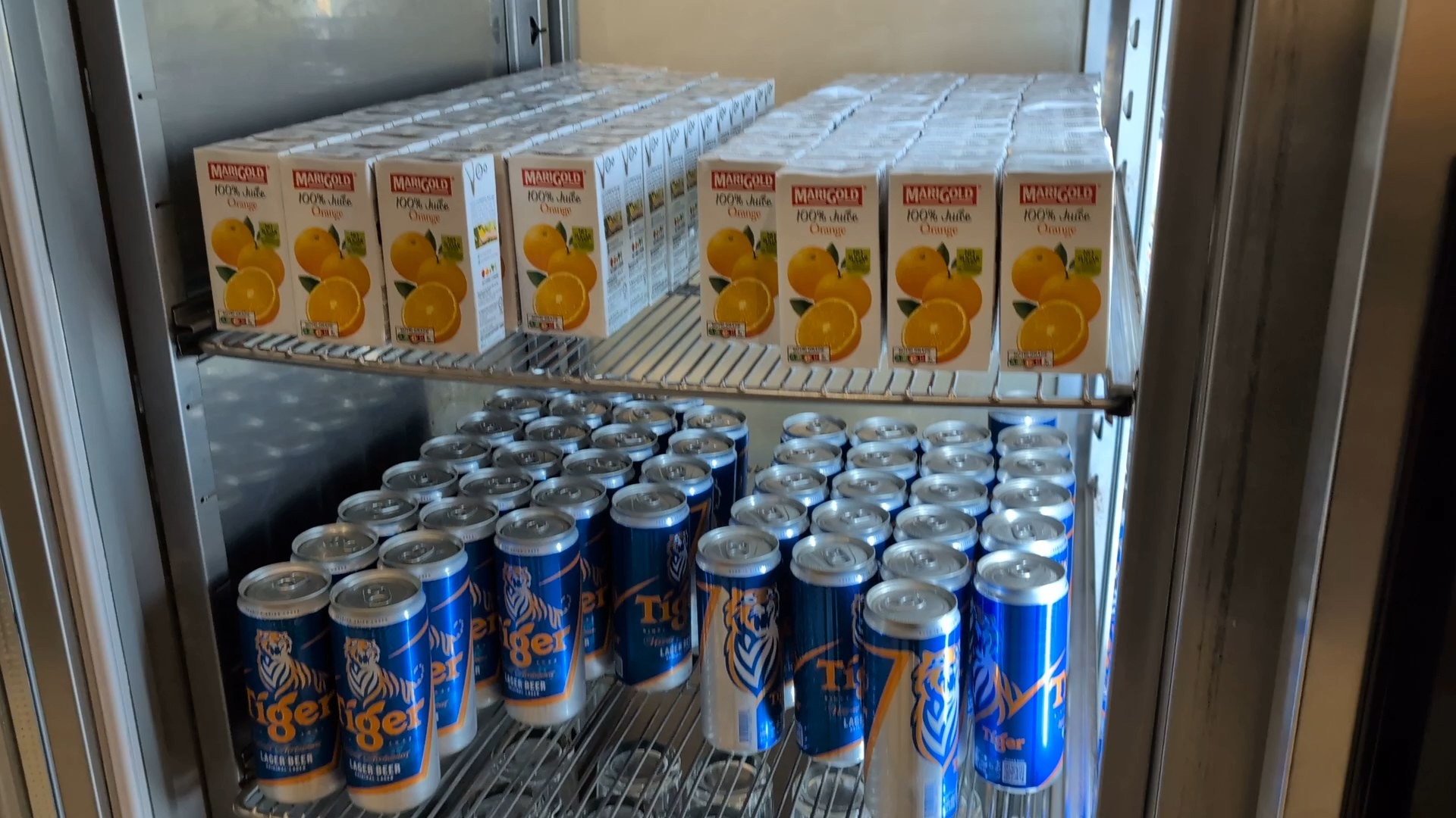 Tiger Lager beer cans stocked in the KrisFlyer Gold Lounge fridge alongside Marigold orange juice.