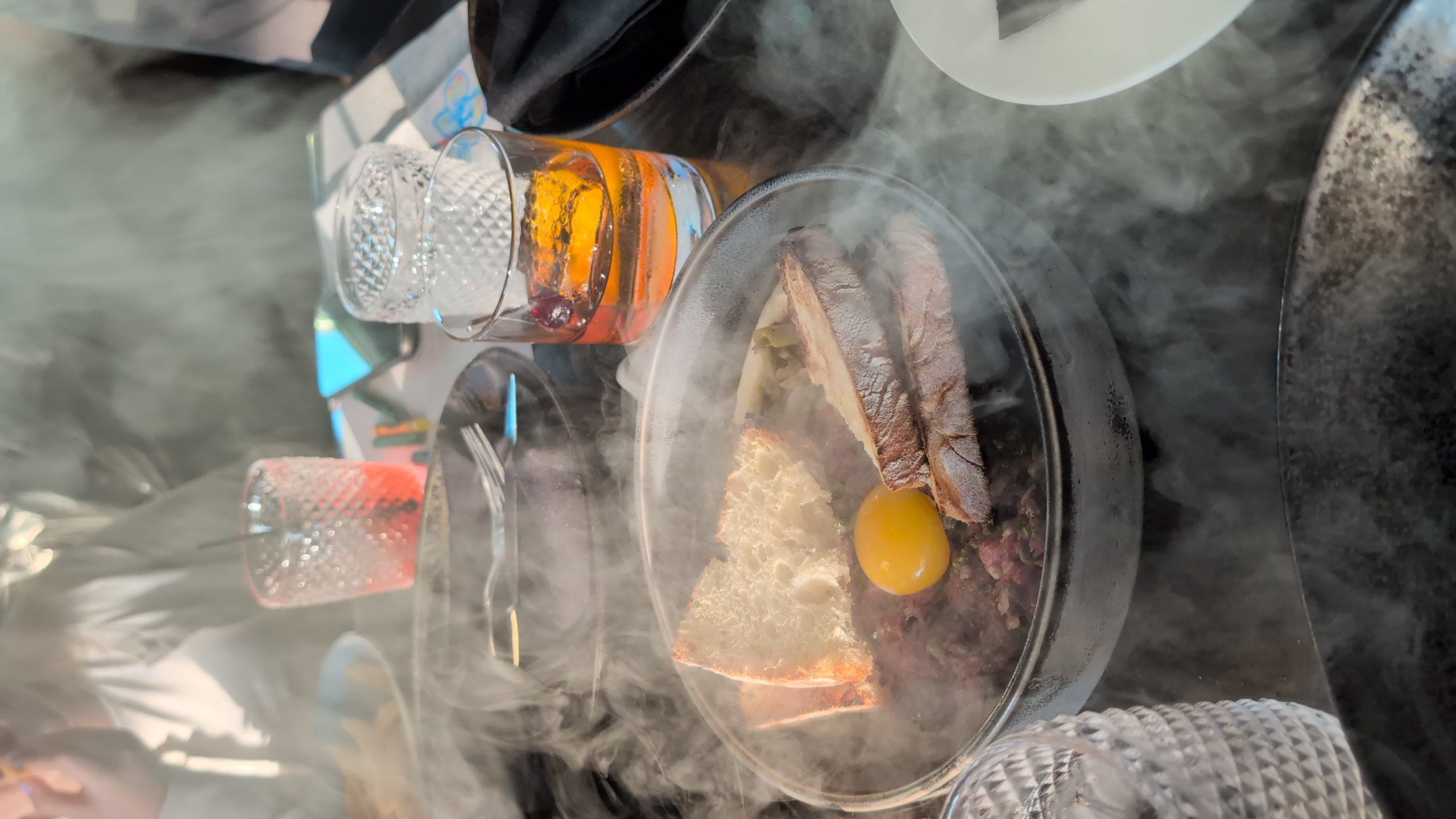 The Smoked Filet Mignon Tartare arriving at the table under a glass dome with smoke pouring across the dish at LAGO Lake Zurich