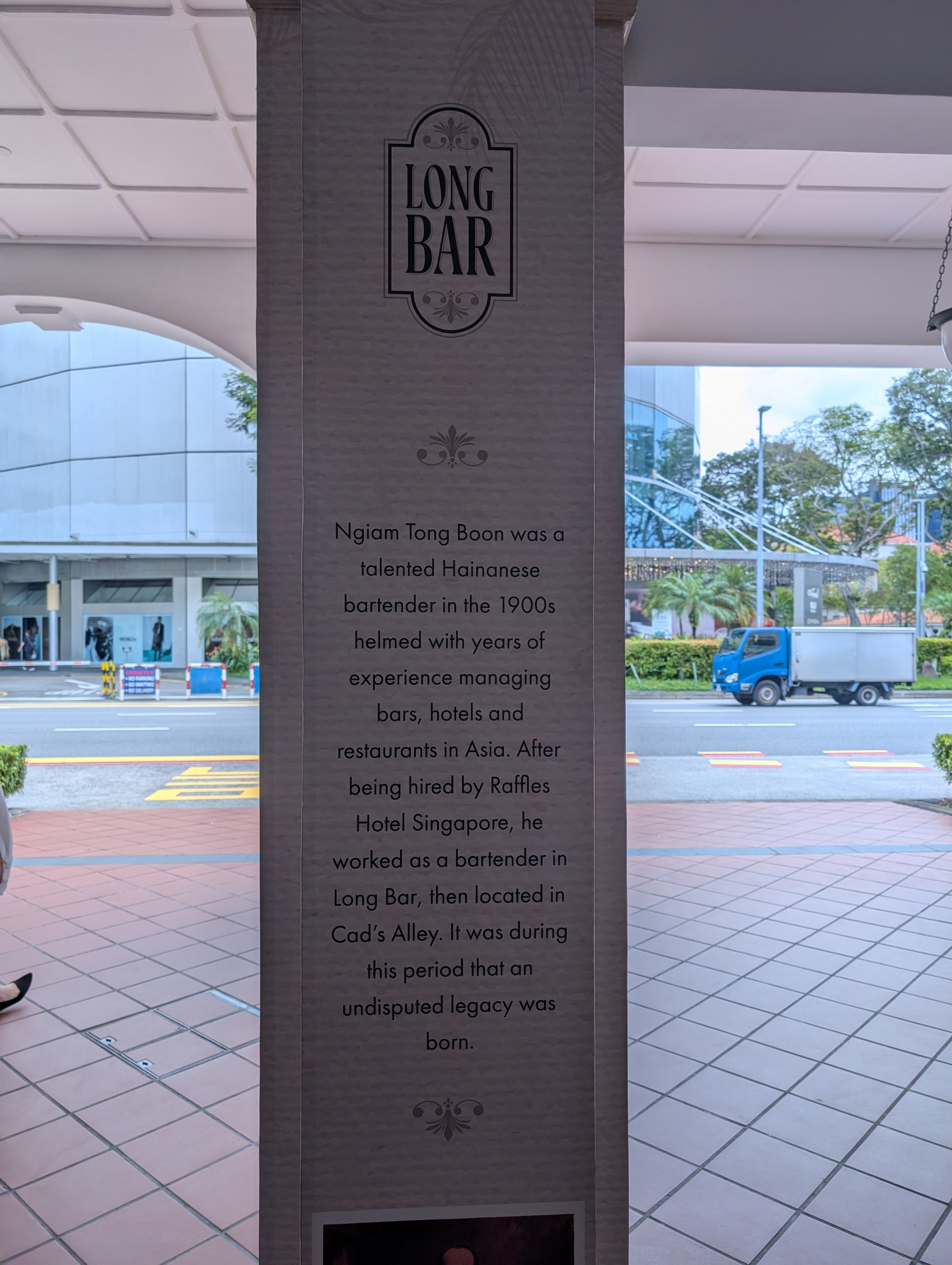 Long Bar entrance pillar at Raffles Hotel Singapore with the Singapore Sling origin story about Hainanese bartender Ngiam Tong Boon