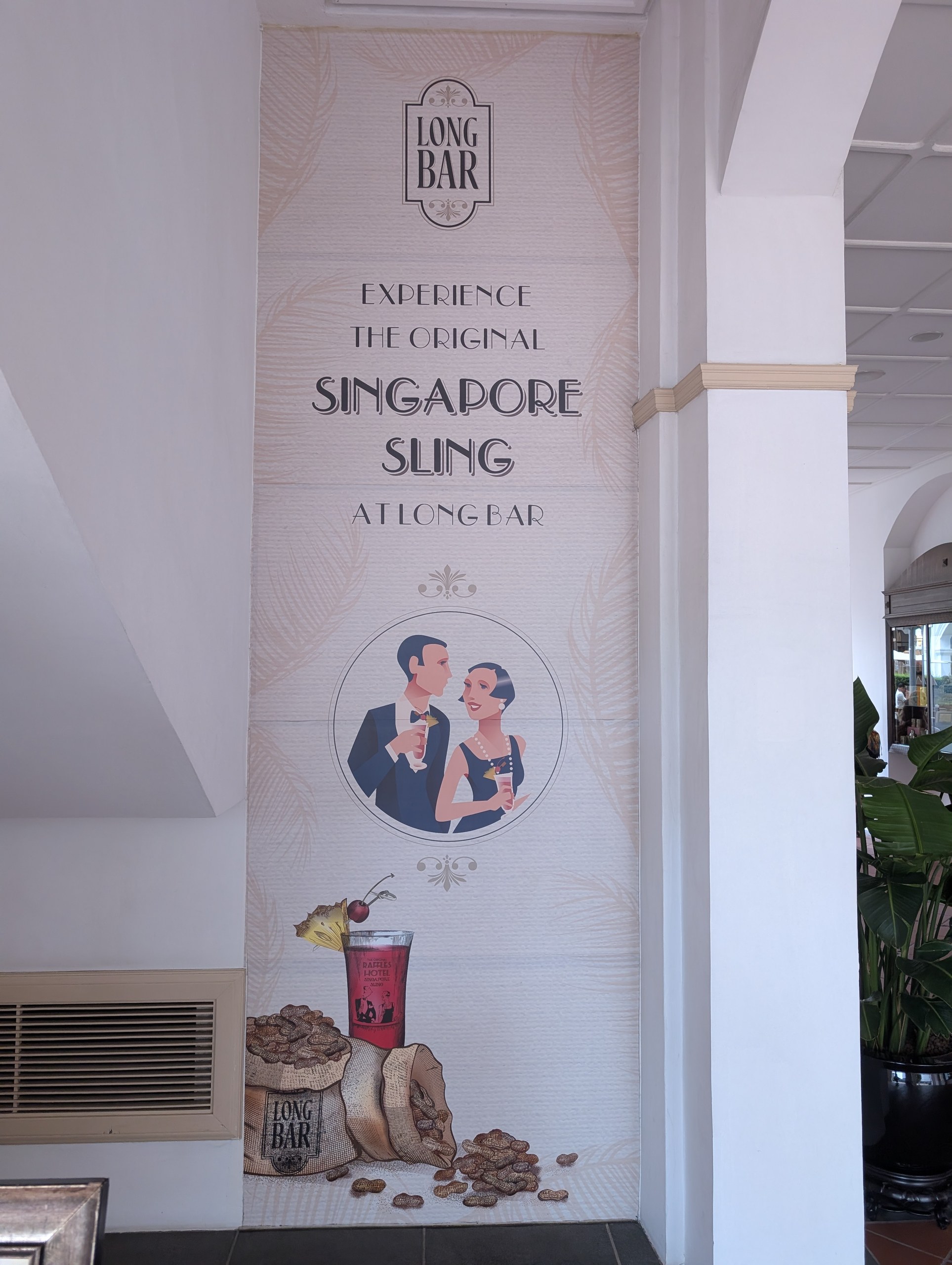 Art Deco wall art at Long Bar with the Singapore Sling, a peanut sack, and an illustrated couple toasting