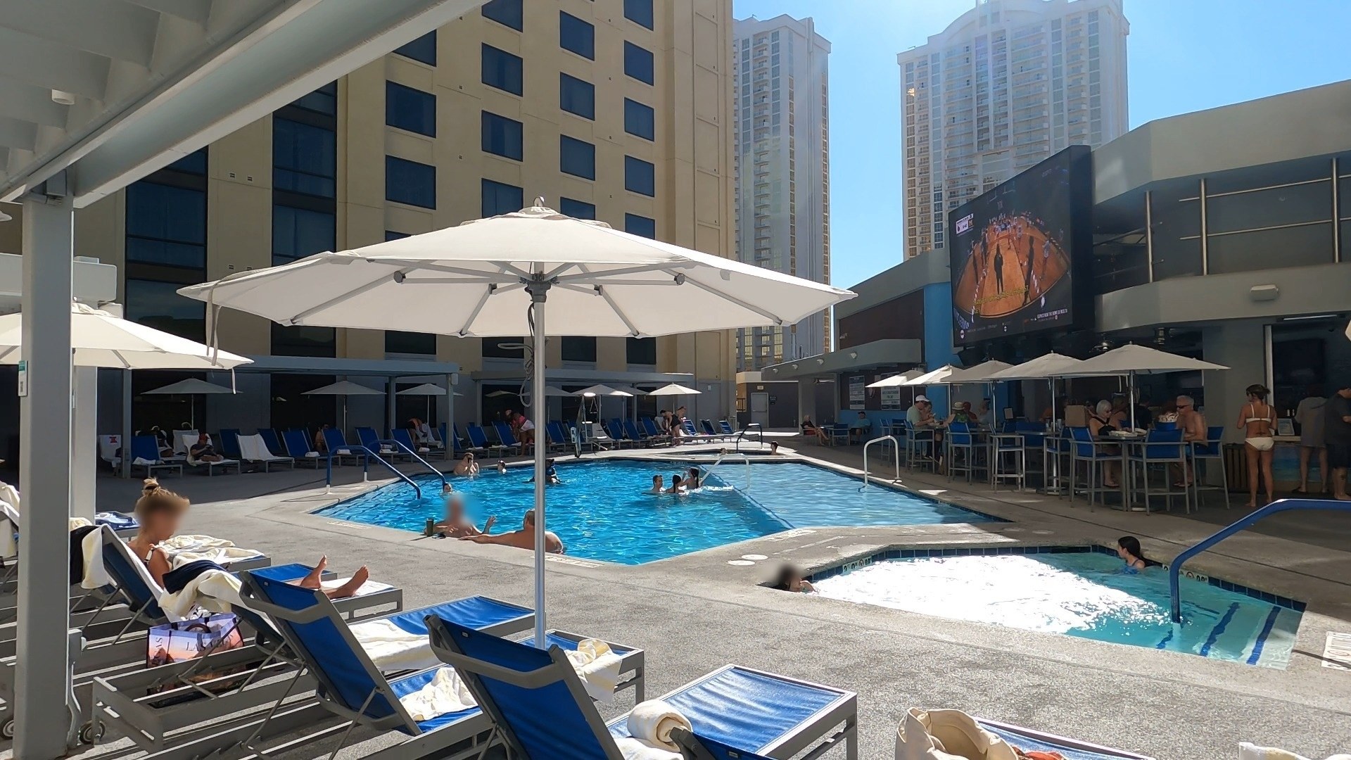 Main pool deck at the Marriott Grand Chateau with umbrellas, hot tub, pool bar and big screen TV