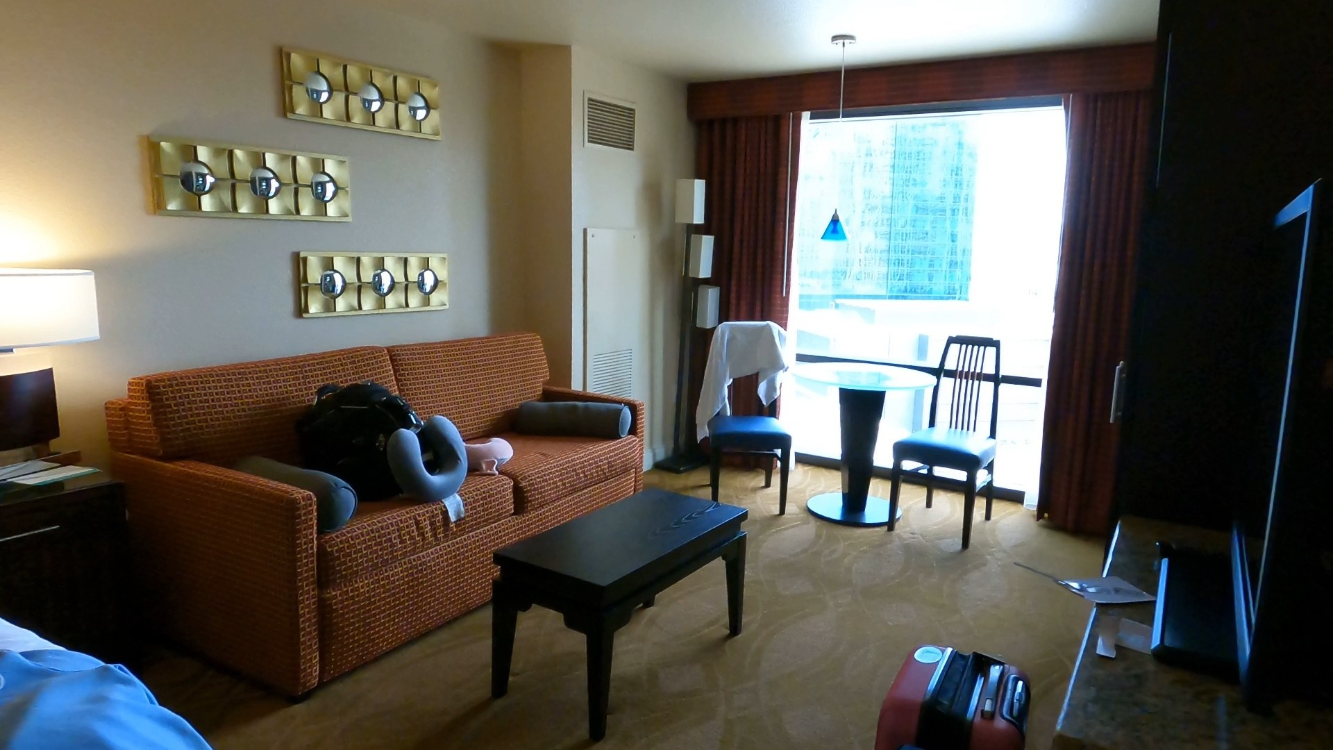 Living room with an orange accent couch and balcony window view in the Marriott Grand Chateau two-bedroom suite