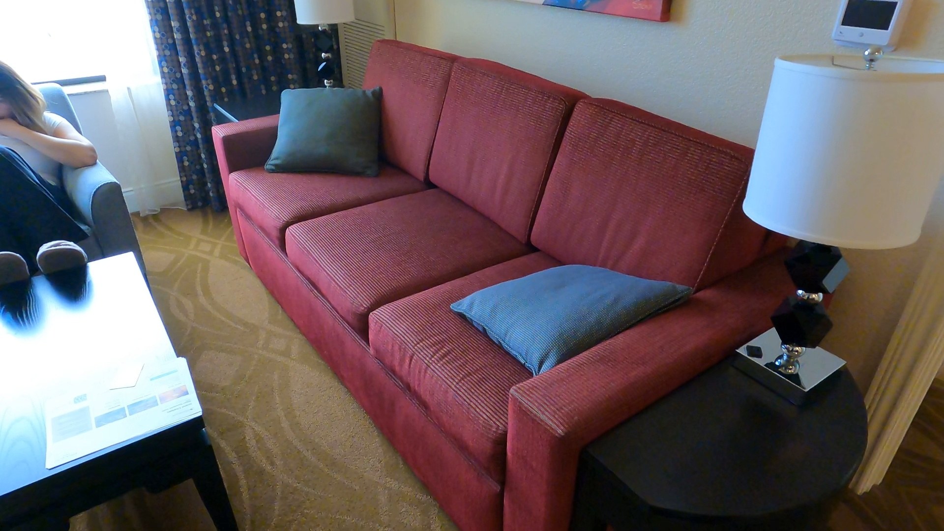 Living room with a red pull-out couch and side table lamp in the Marriott Grand Chateau two-bedroom suite