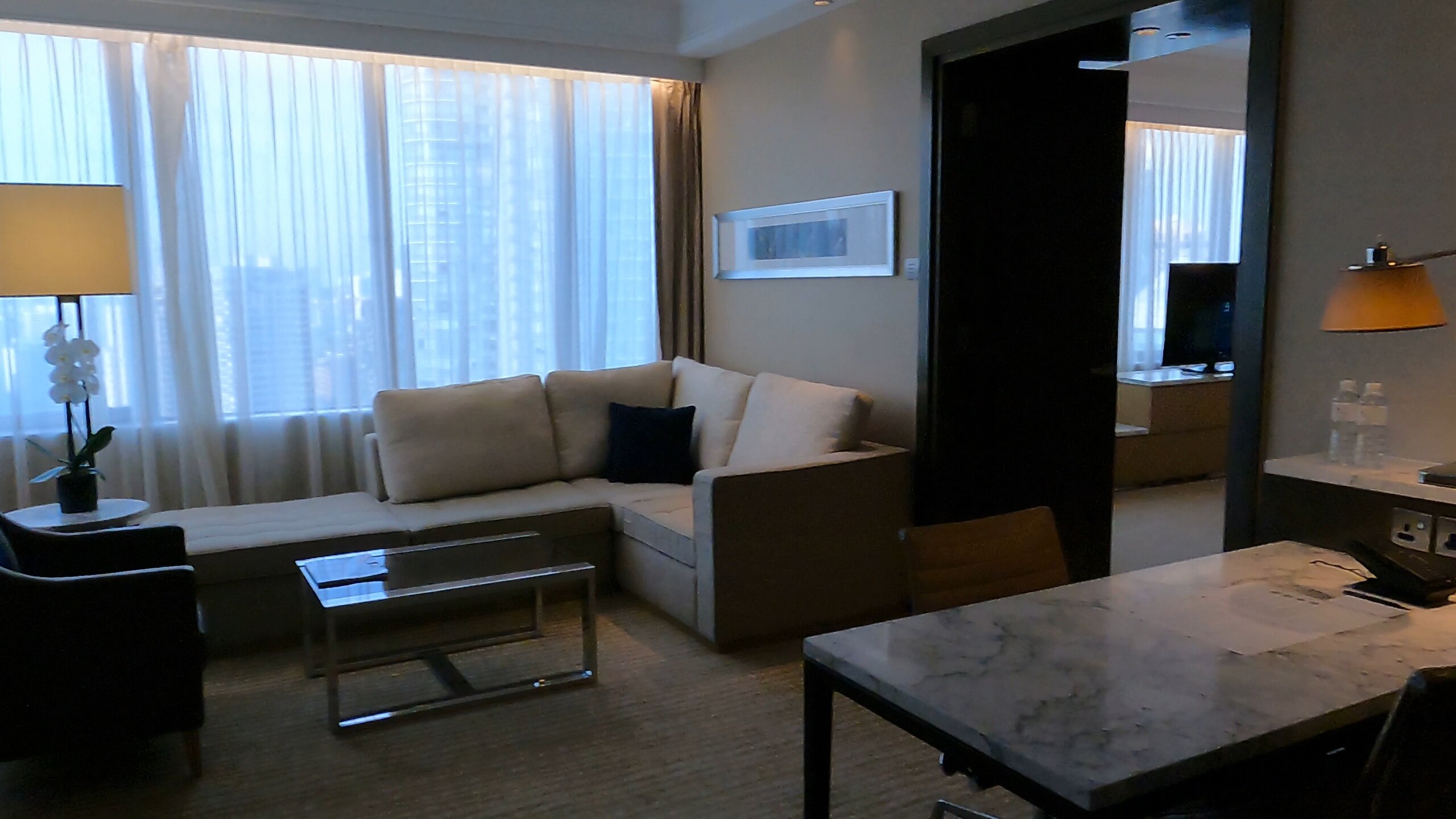 Executive Suite living room with sectional sofa and marble dining table at the Singapore Marriott Tang Plaza