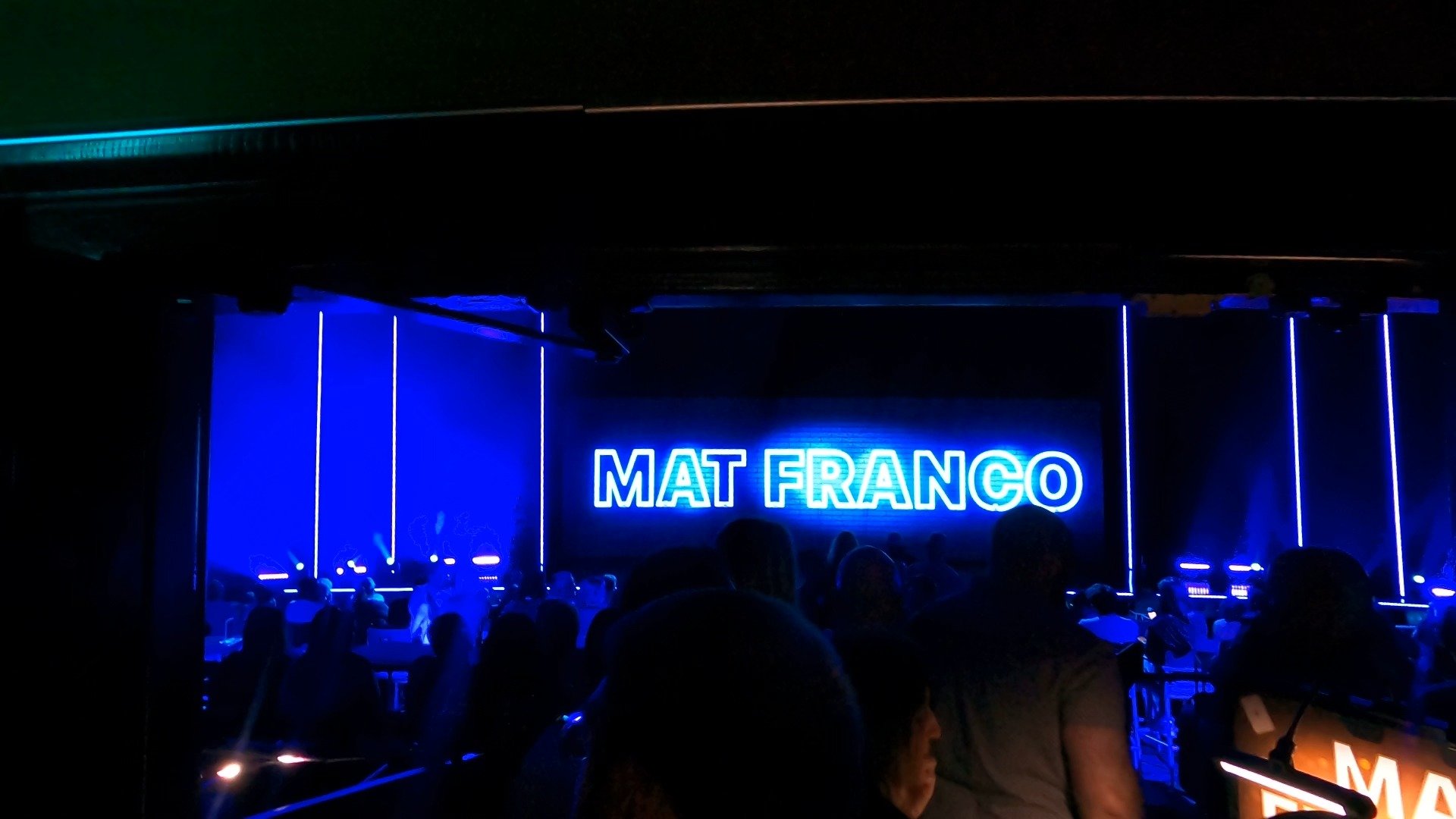View of the Mat Franco stage with the blue neon sign from the premium couch seats at The Linq