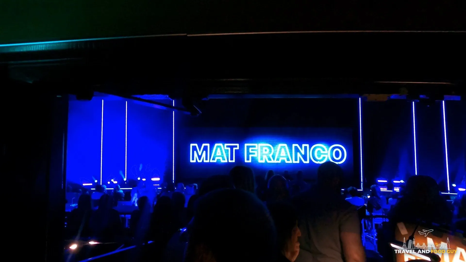 View of the Mat Franco stage with the blue neon sign from the premium couch seats at The Linq