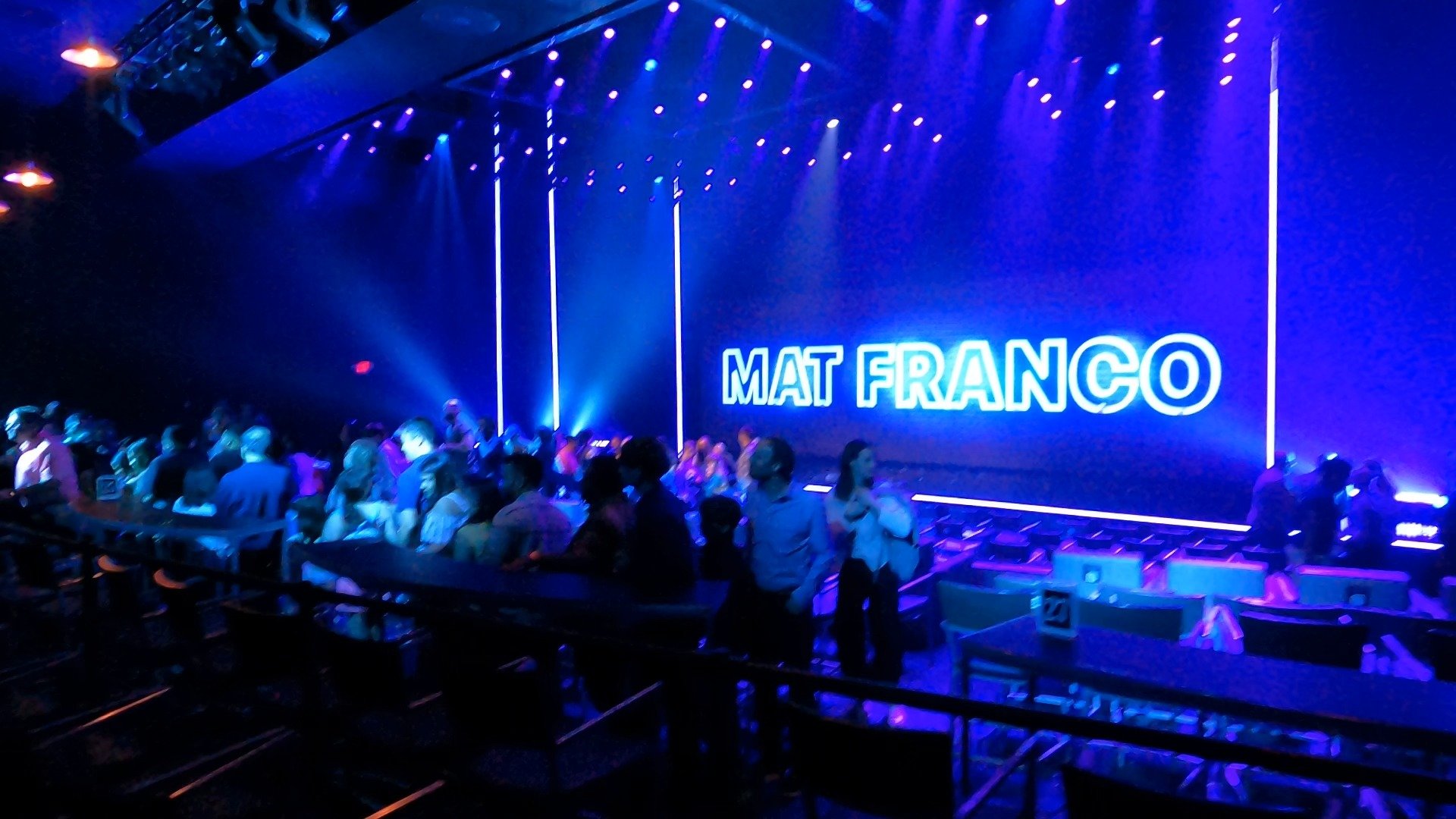 Wide view of the Mat Franco theater at The Linq with the Mat Franco neon sign on stage and the audience filing in