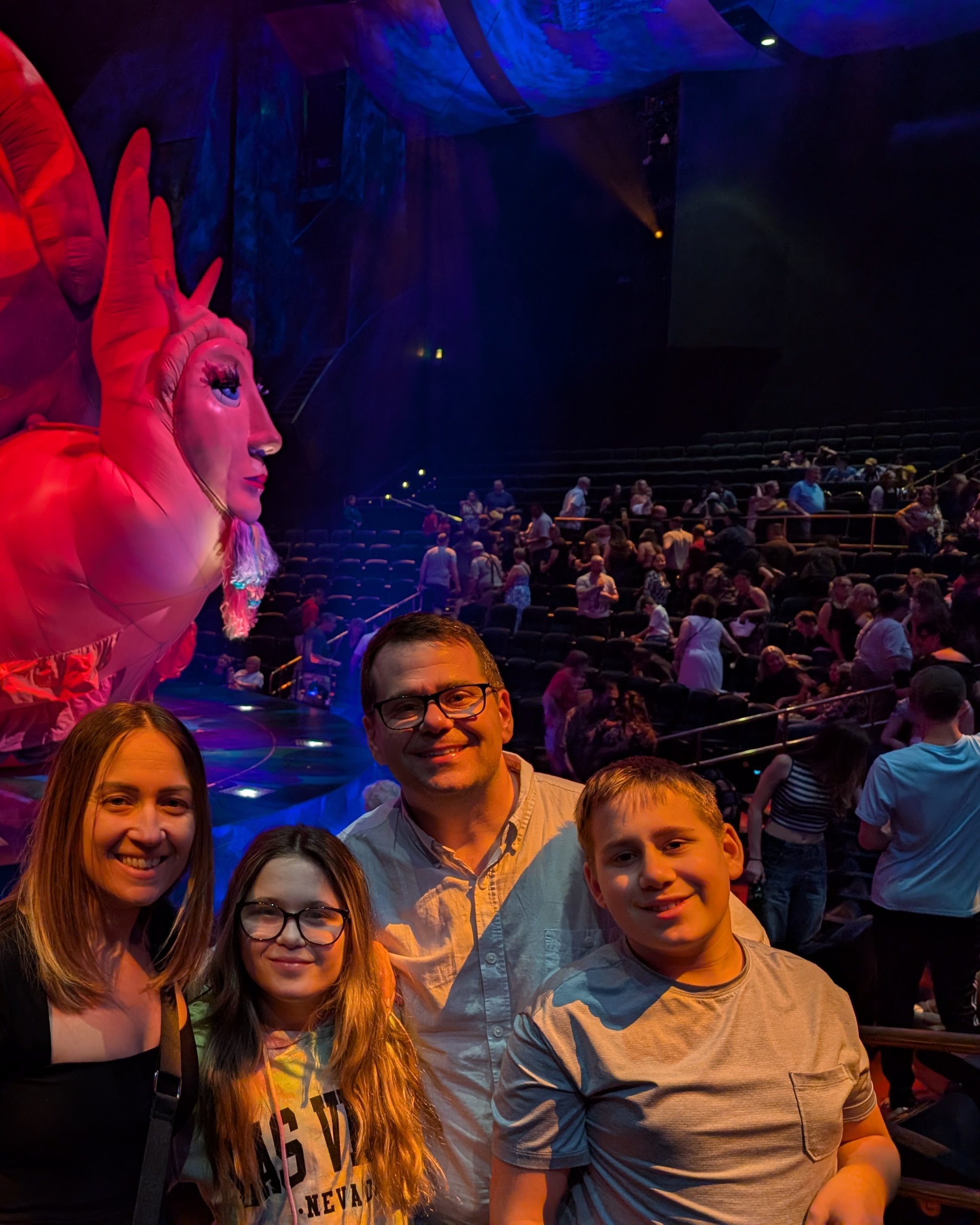 Alex, Vika, Josh, and Emily posing at the Mystère theater with the giant red snail prop in the background