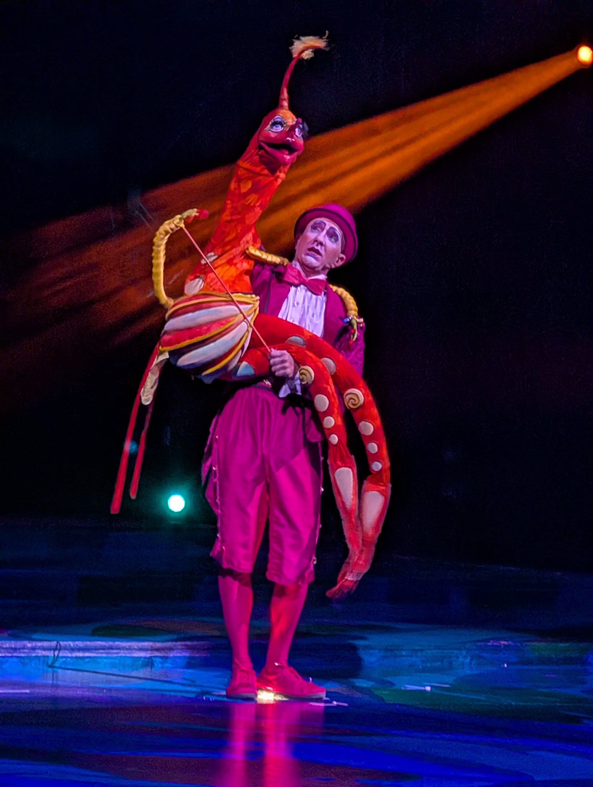 A Mystère performer holding a large red sea creature puppet on the Treasure Island stage