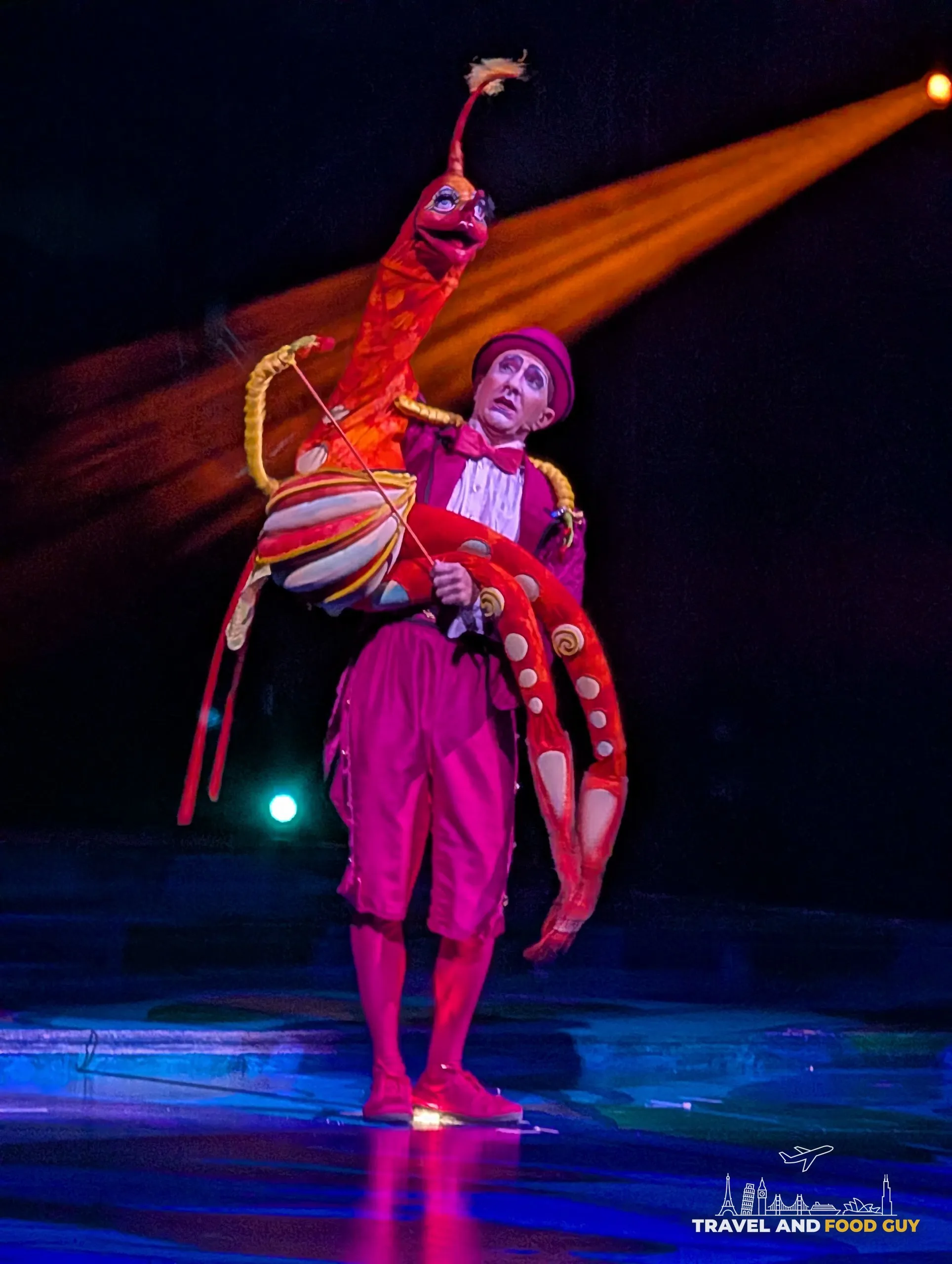 A Mystère performer holding a large red sea creature puppet on the Treasure Island stage