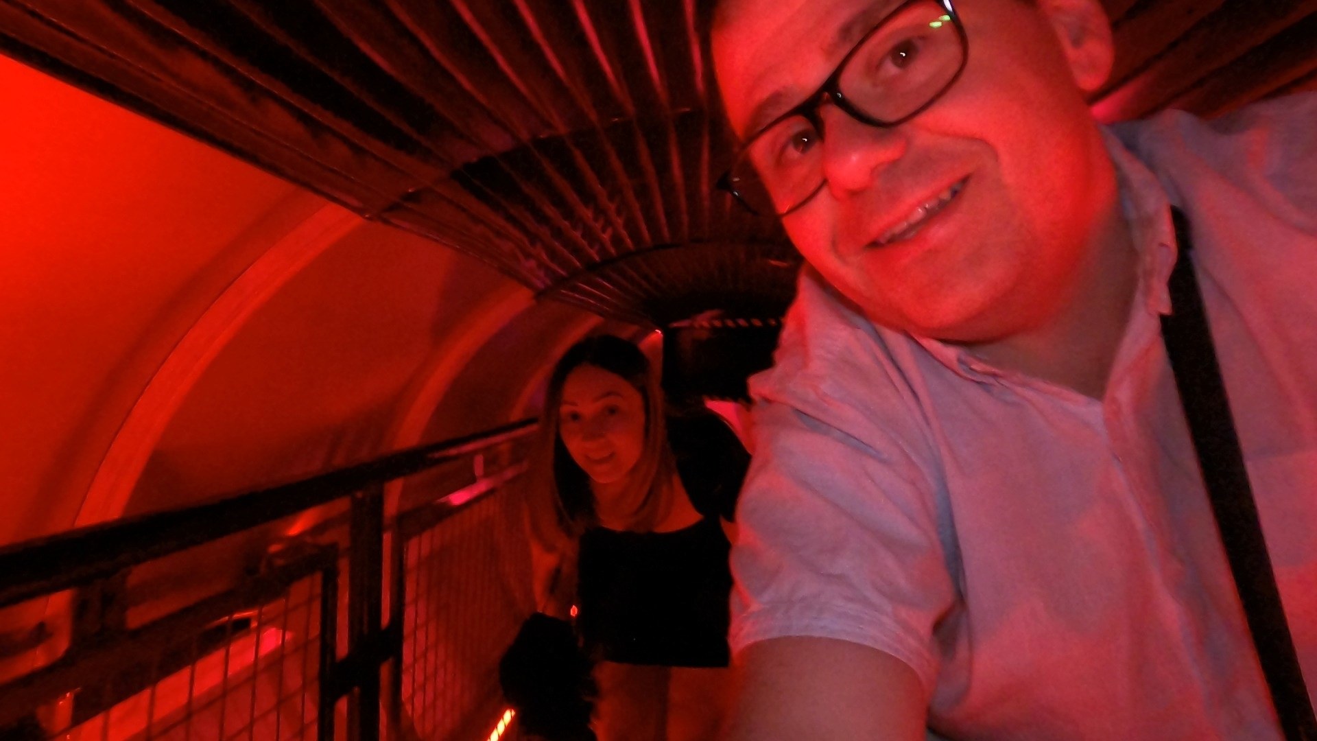 Alex and Vika in a selfie inside the red lit Omega Mart tunnel walkway