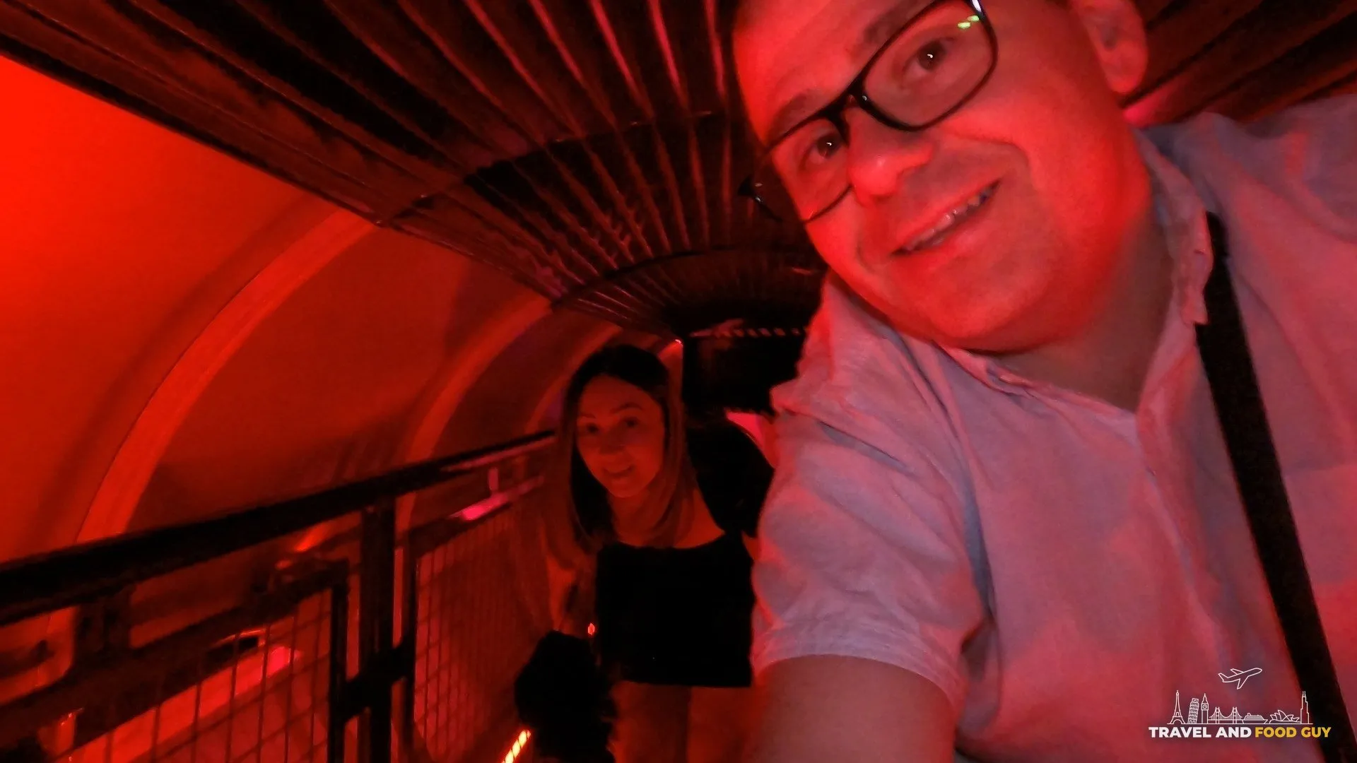 Alex and Vika in a selfie inside the red lit Omega Mart tunnel walkway