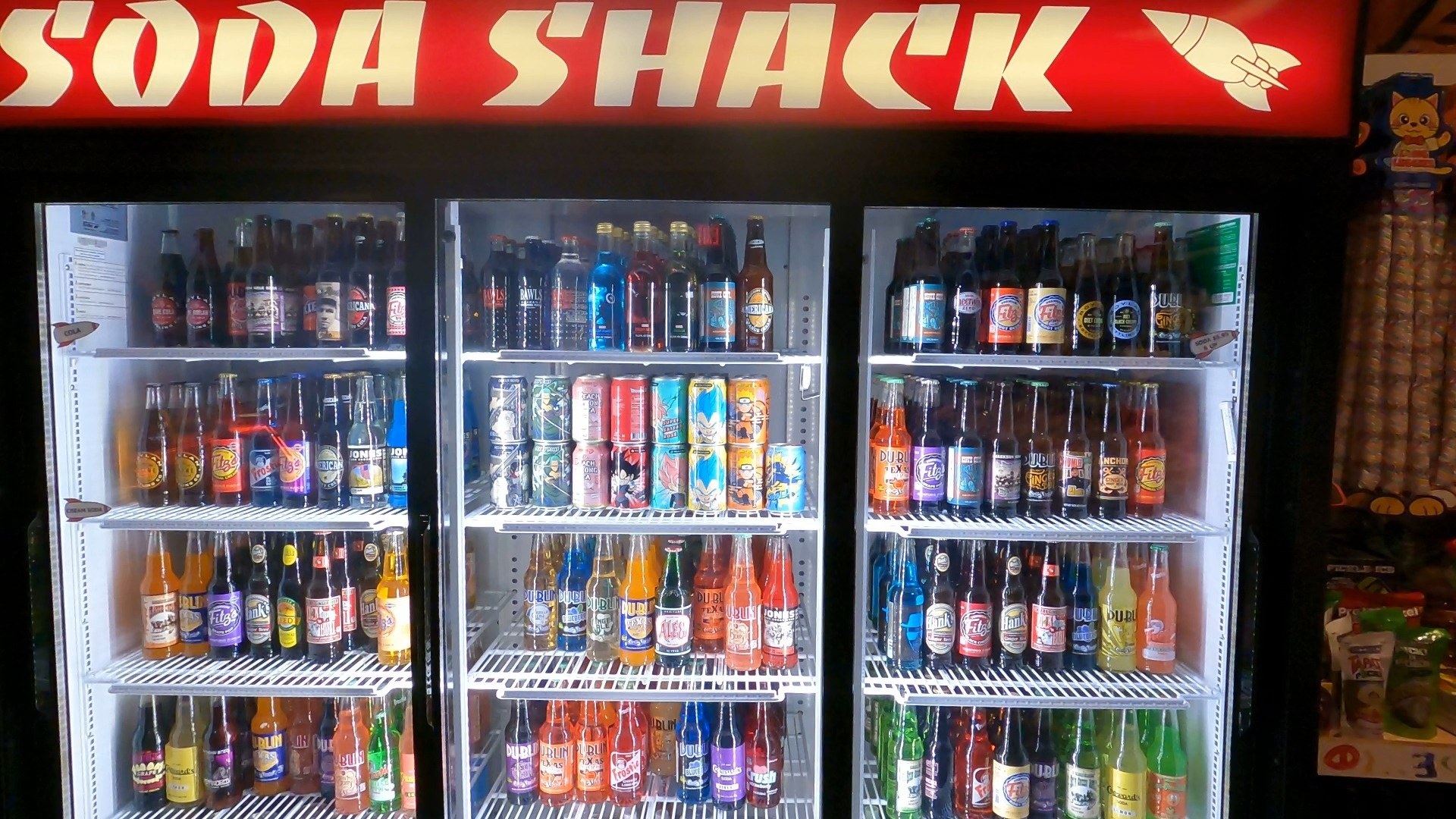 Soda Shack glass bottle wall at Omega Mart with rows of vintage and novelty sodas inside Area 15