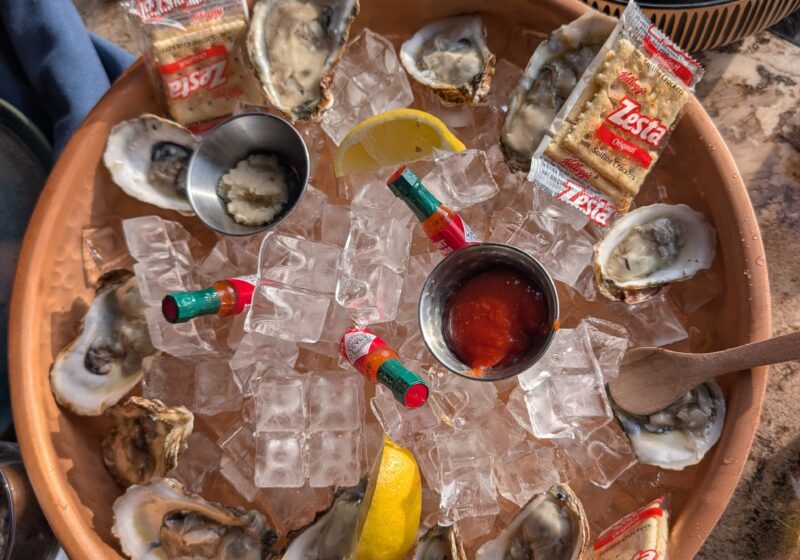 A dozen east coast oysters on a clay platter of ice with lemon wedges, hot sauce and crackers at Ostras Lounge in Des Plaines.